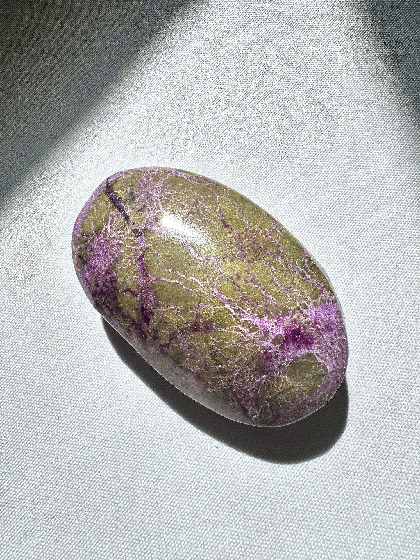 Polished Atlantisite Crystal Palm Stone featuring vivid green serpentine and purple stichtite patterns, ideal for emotional healing rituals.