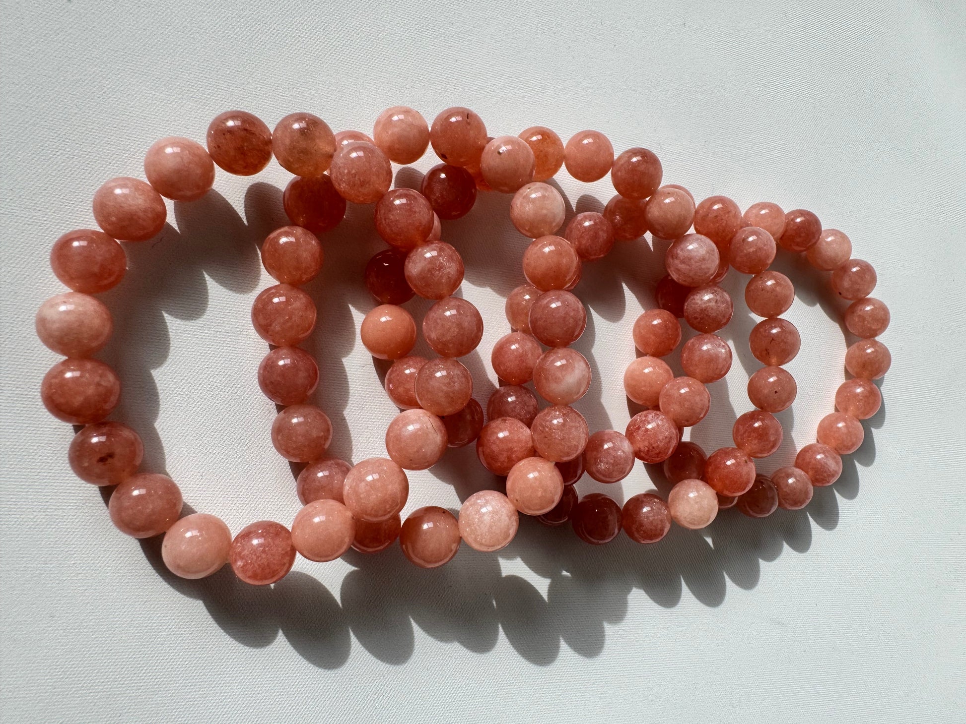Multiple Sunstone Crystal Bracelets 10mm with radiant orange-pink hues, perfect for jewelry lovers seeking creativity and positive energy.