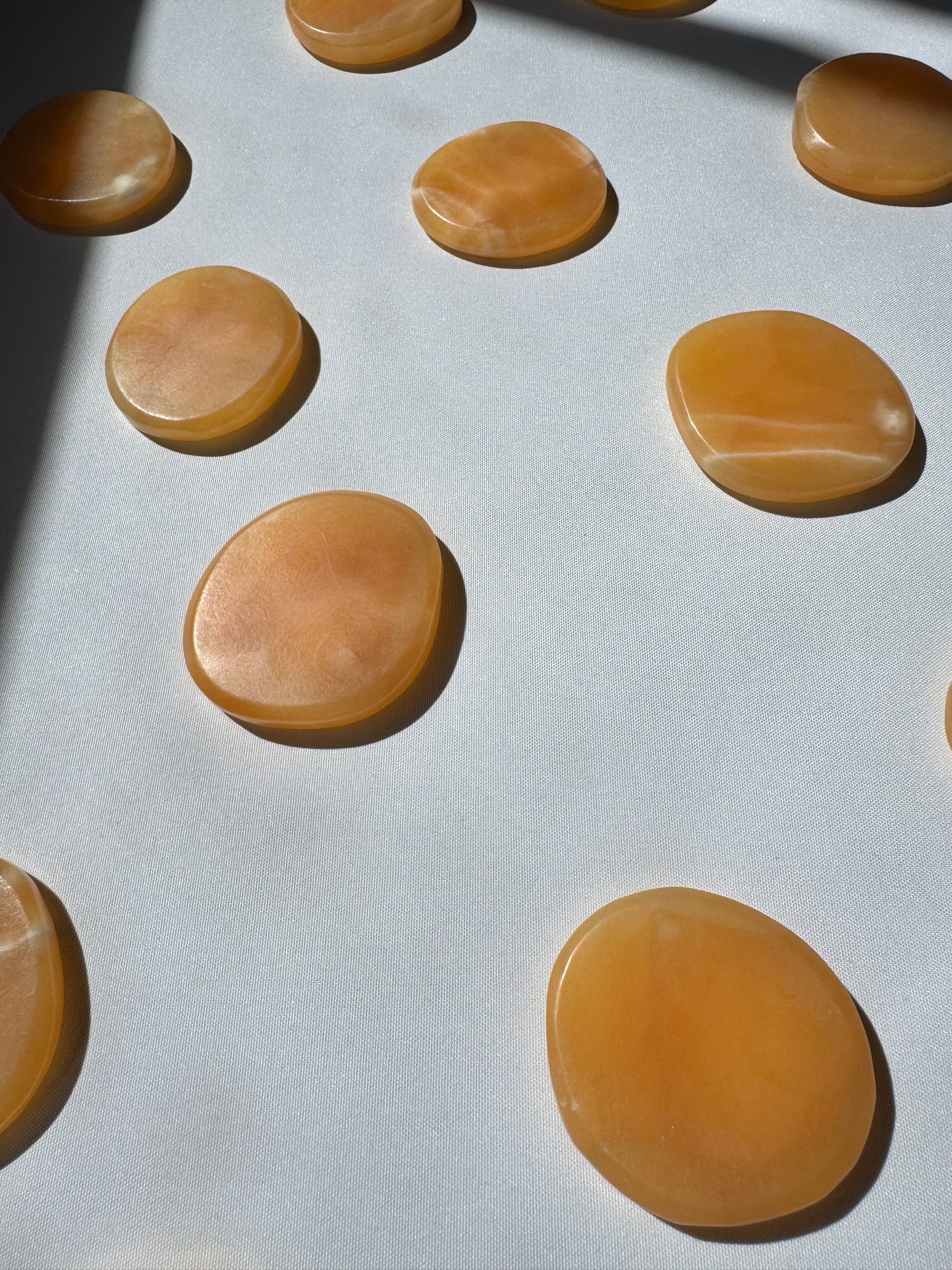 Multiple Orange Calcite Crystal Sun Discs | Bespoke Crystals arranged in sunlight, highlighting their radiant glow and collectible quality.