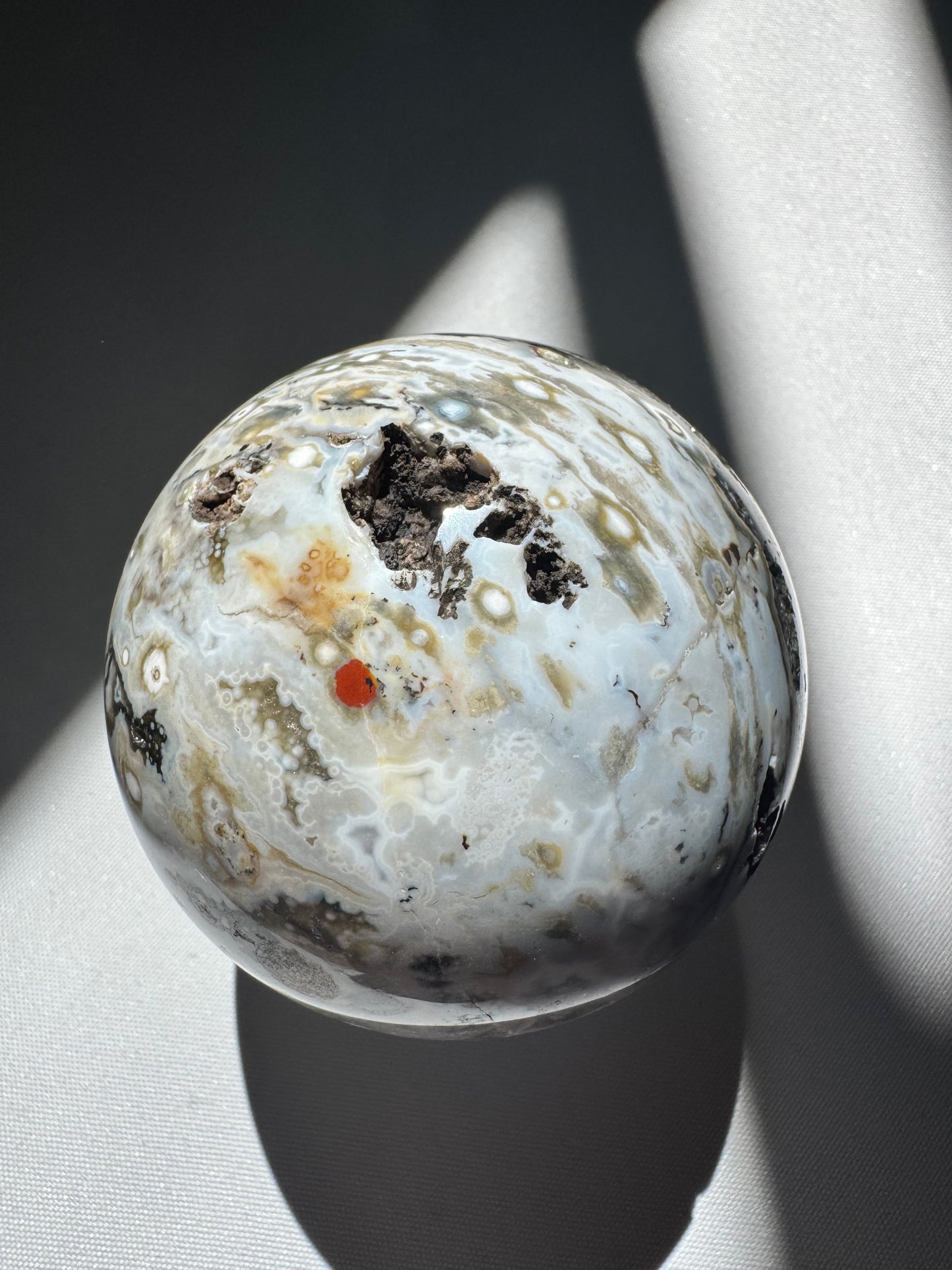 Orbicular Ocean Jasper Sphere #4 with light blue, white, and earthy tones, highlighted by a vivid red orb and natural inclusions | Buy Crystals Online NZ
