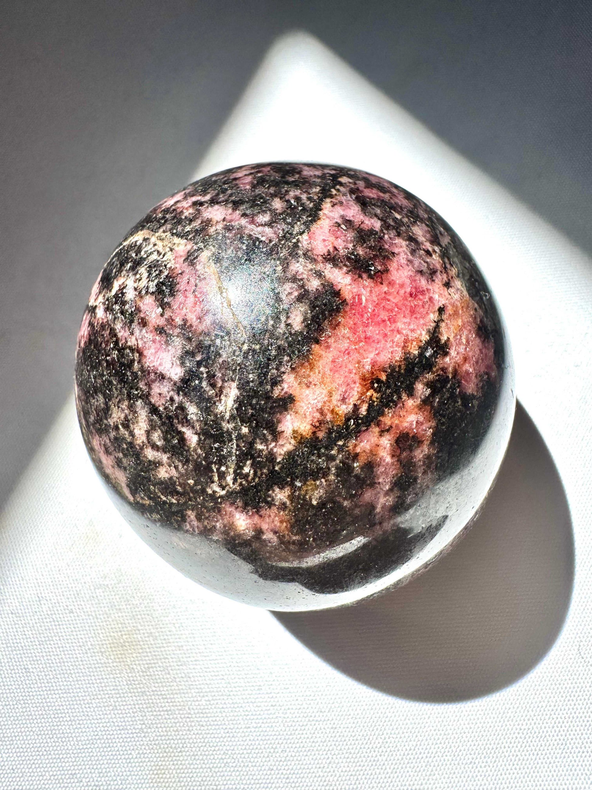 Rhodonite Sphere -  Unique Rhodonite gemstone sphere with vibrant pink and dark mineral patterns, ideal for collectors.