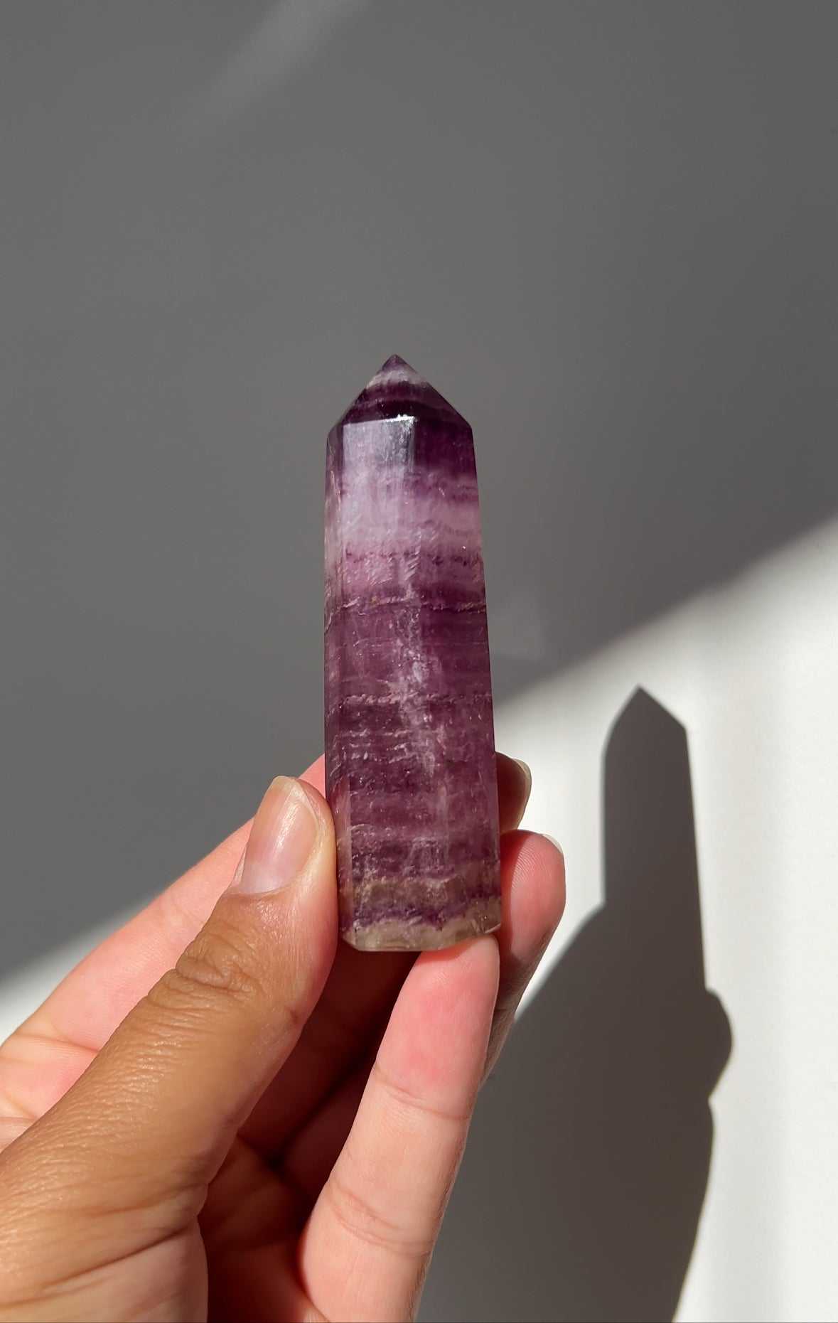 Magenta Fluorite Point - Crystals NZ held in hand, showcasing vibrant purple layers ideal for enhancing psychic abilities and clarity in crystal healing.