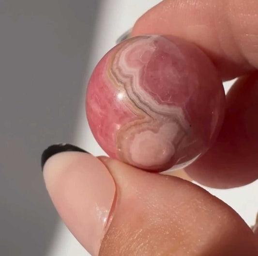 Close-up of a High Quality Rhodochrosite Crystal Mini Sphere showing detailed pink and cream banding, perfect for bespoke crystal collections | Bespoke Crystals