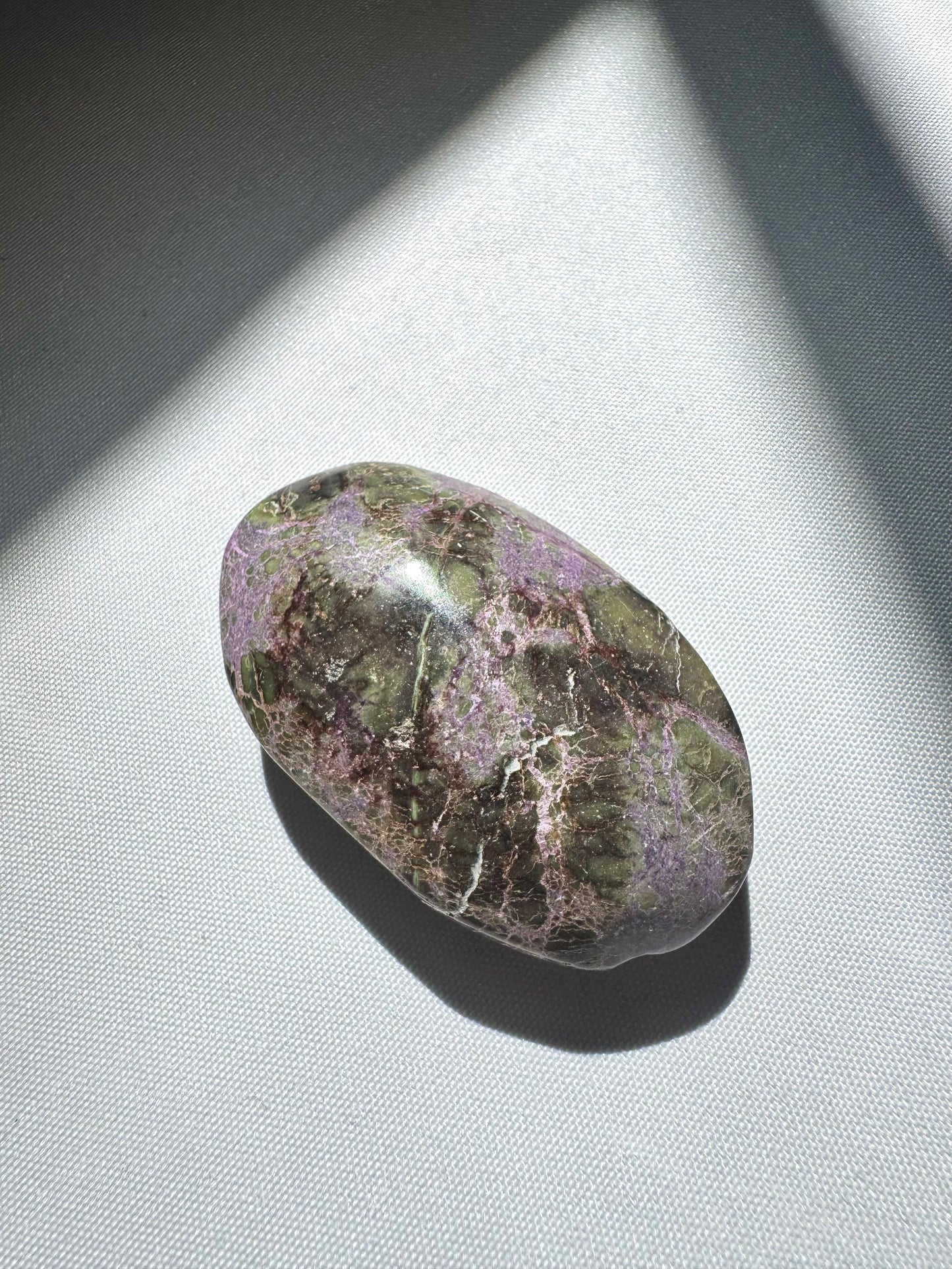 Glossy Atlantisite Crystal Palm Stone with earthy green and violet tones, symbolizing balance and higher realm connection.