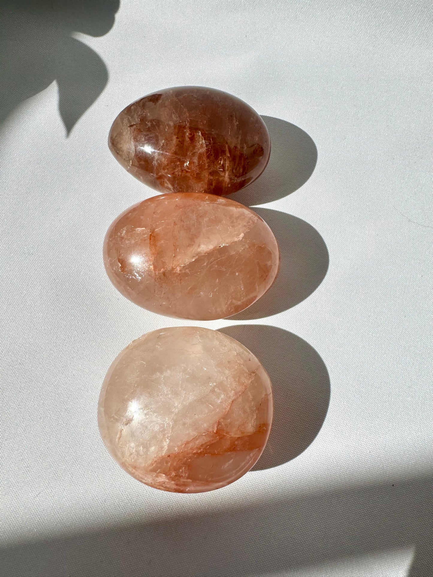 Vertical arrangement of Fire Quartz Crystal Palm Stones showcasing natural hematite inclusions and polished finish for collectors and crystal healing.