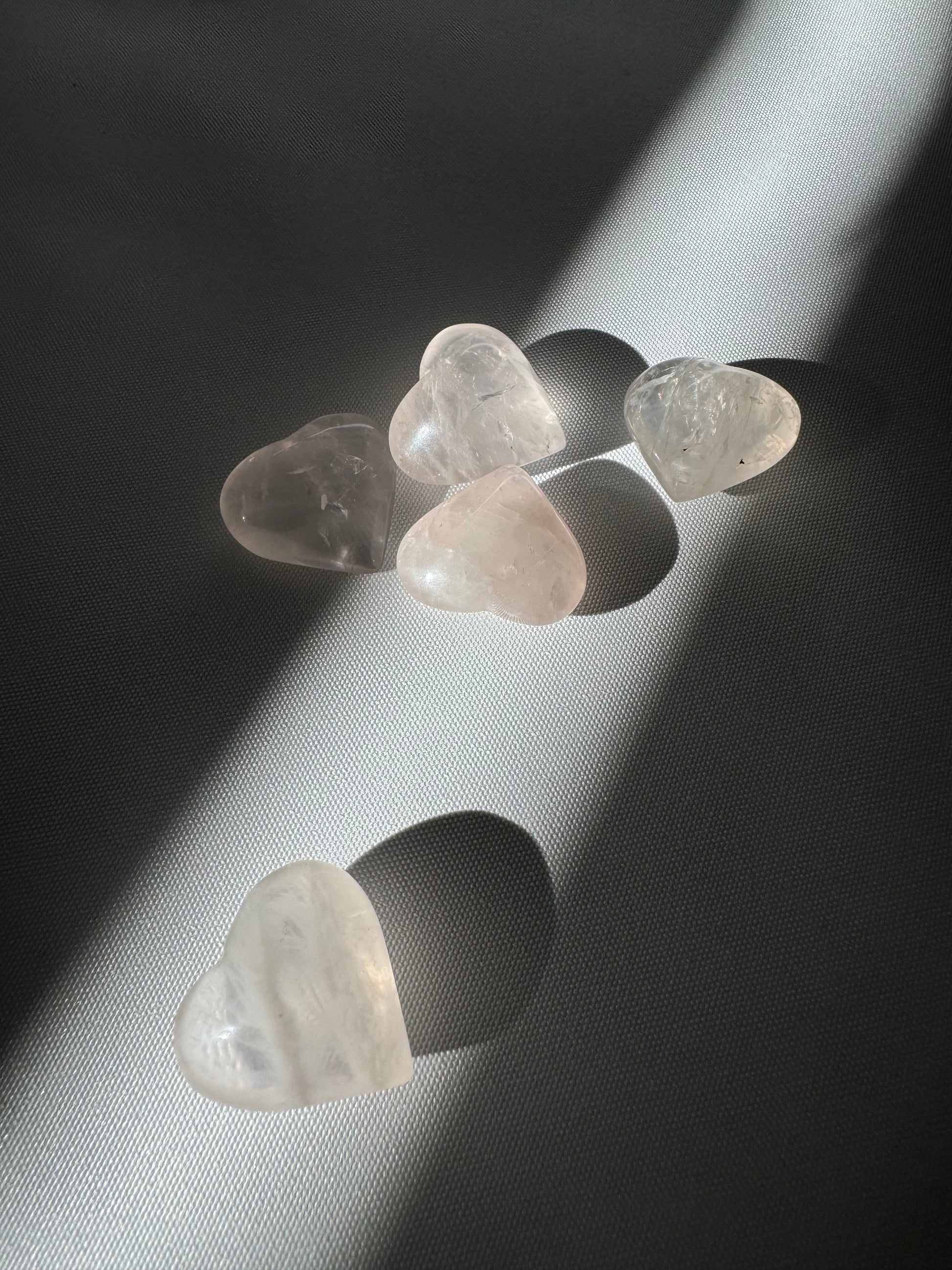 Mini Rose Quartz Crystal Hearts | Bespoke Crystals scattered on a textured surface under natural light, ideal for collectors and crystal enthusiasts.