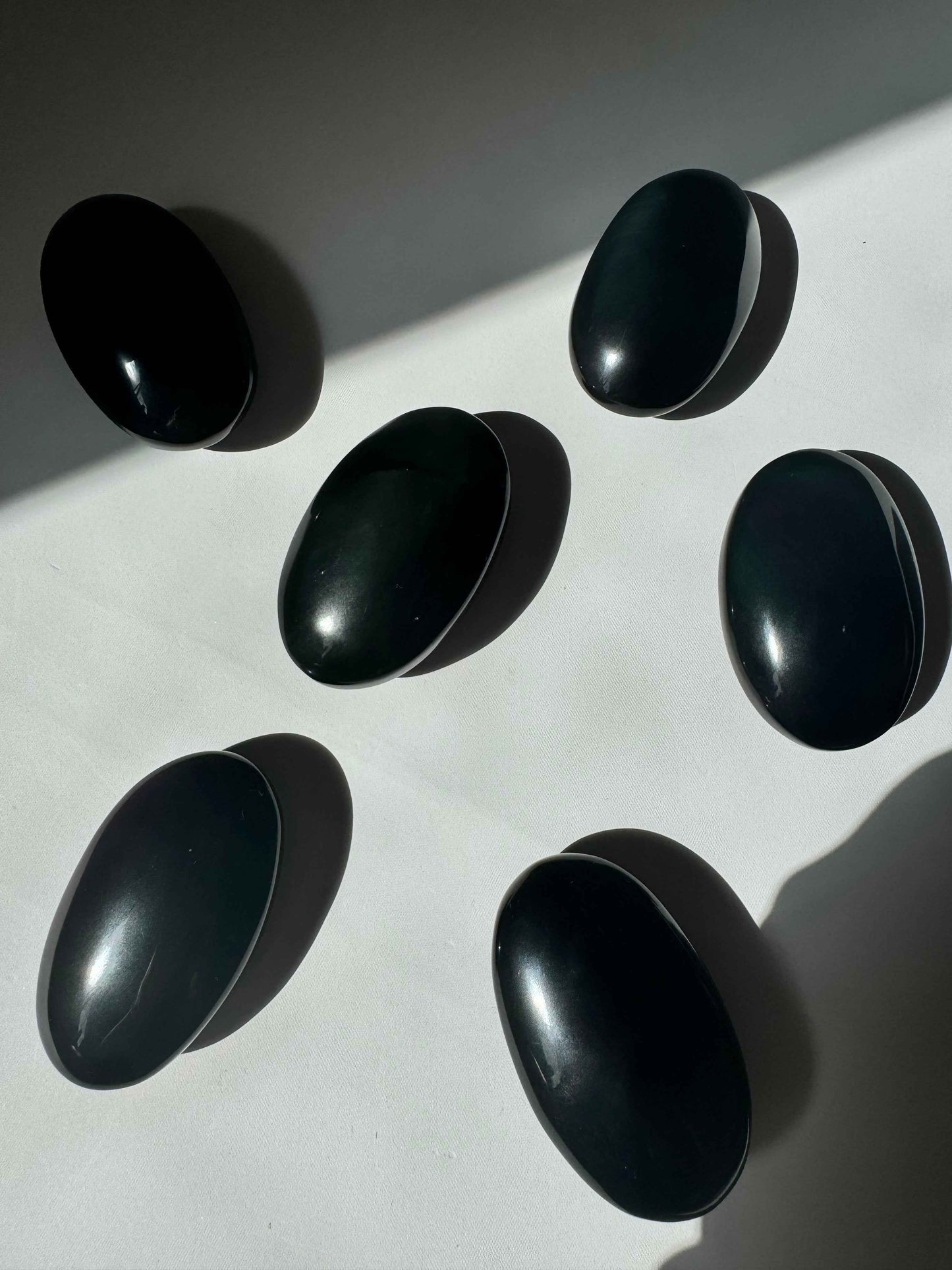 Six Rainbow Obsidian Crystal Palm Stones with subtle color reflections, perfect for collectors and crystal healing enthusiasts.