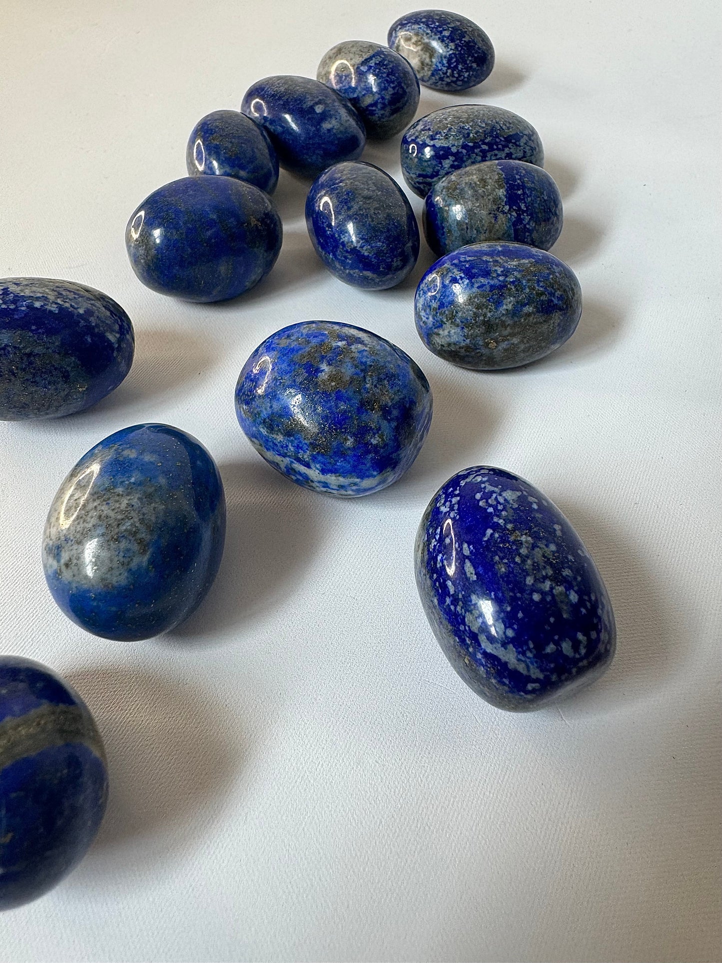Collection of Lapis Lazuli Crystal Tumble Stones arranged diagonally, featuring vibrant blue tones