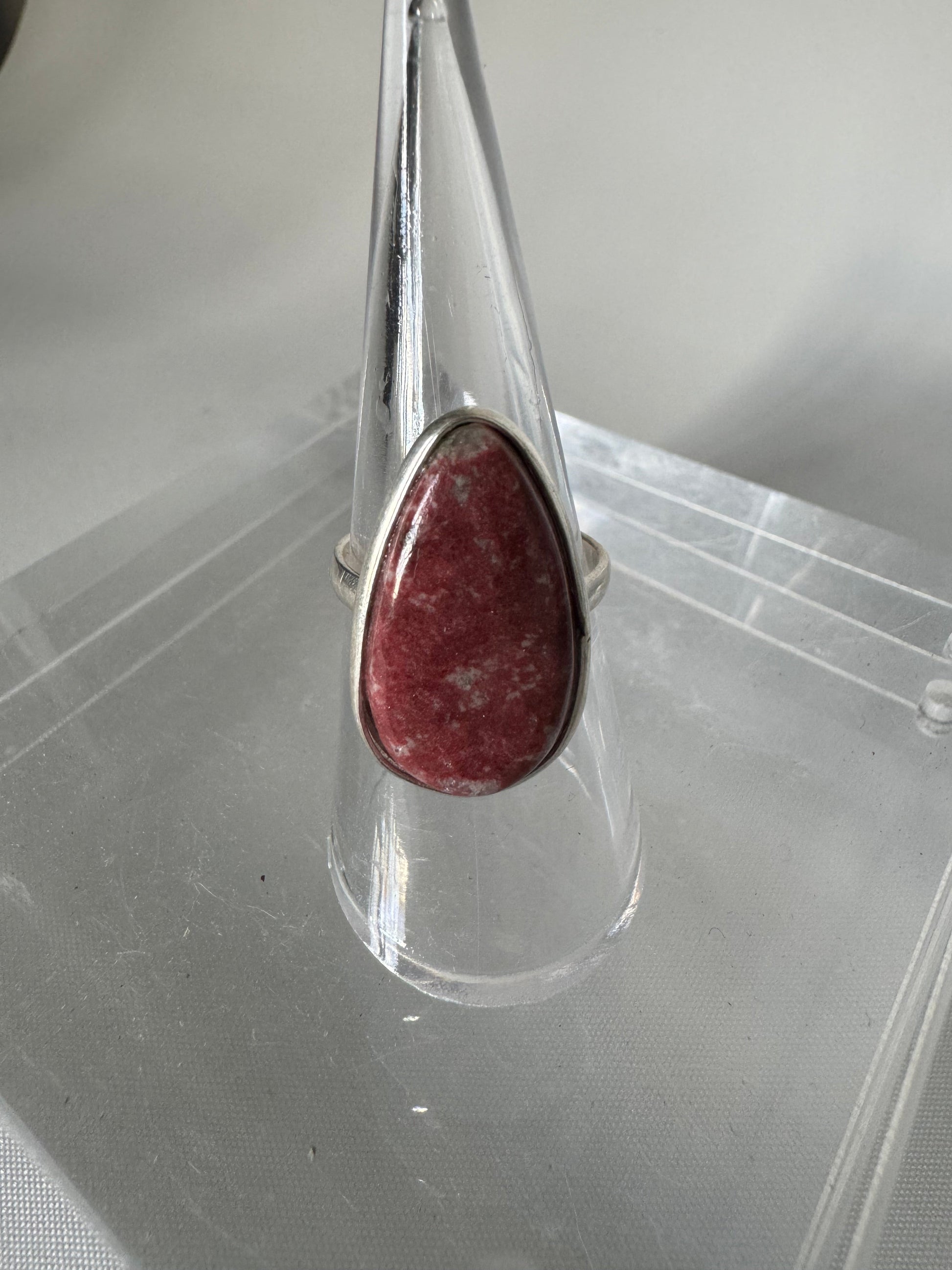 Thulite Crystal Ring | Bespoke Crystals featuring a teardrop-shaped pink Thulite stone set in sterling silver, displayed on a clear stand.