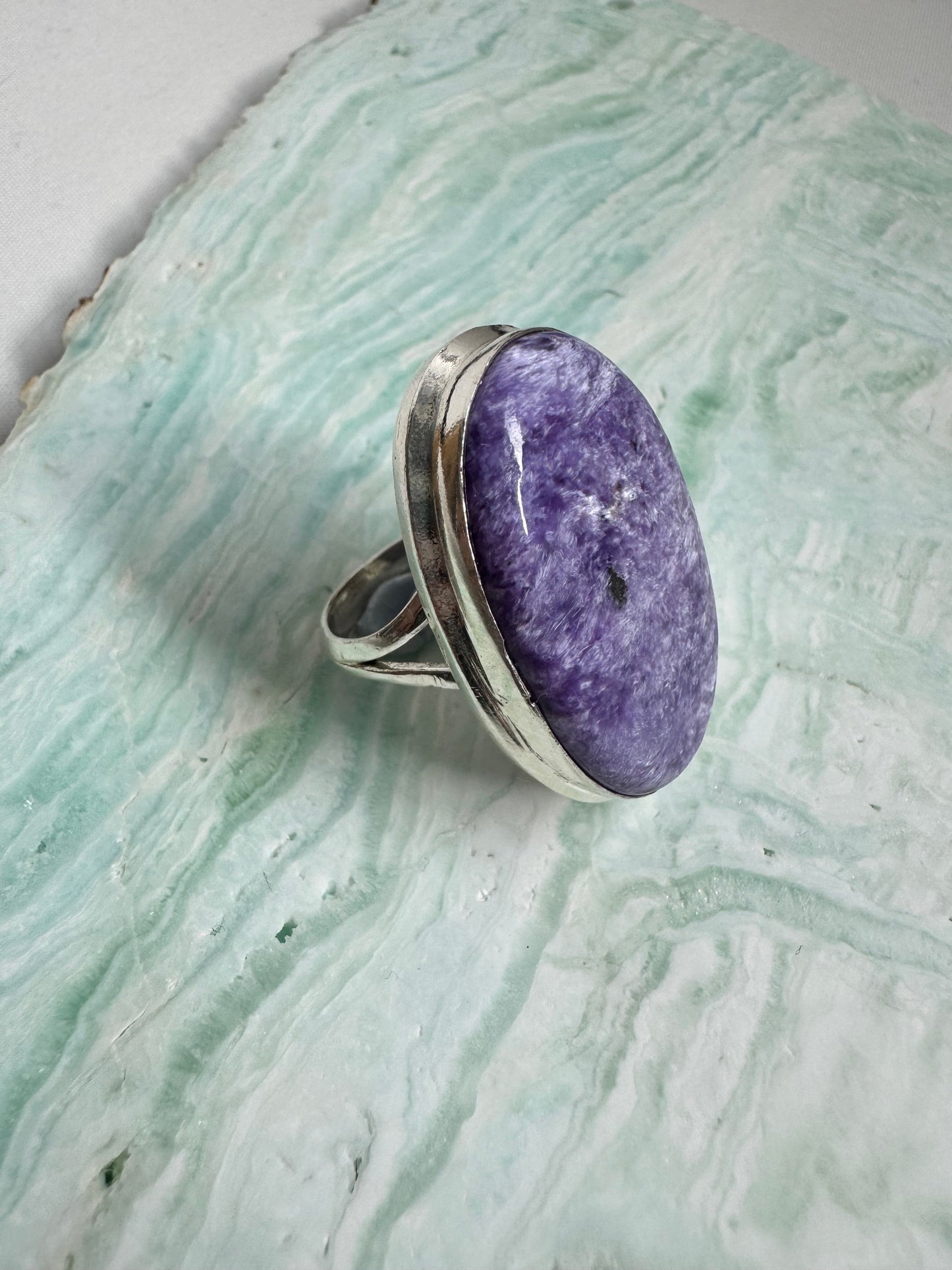 Angled view of Large Charoite Crystal Ring highlighting the textured purple gemstone and sterling silver band, a bold accessory in gemstone rings.