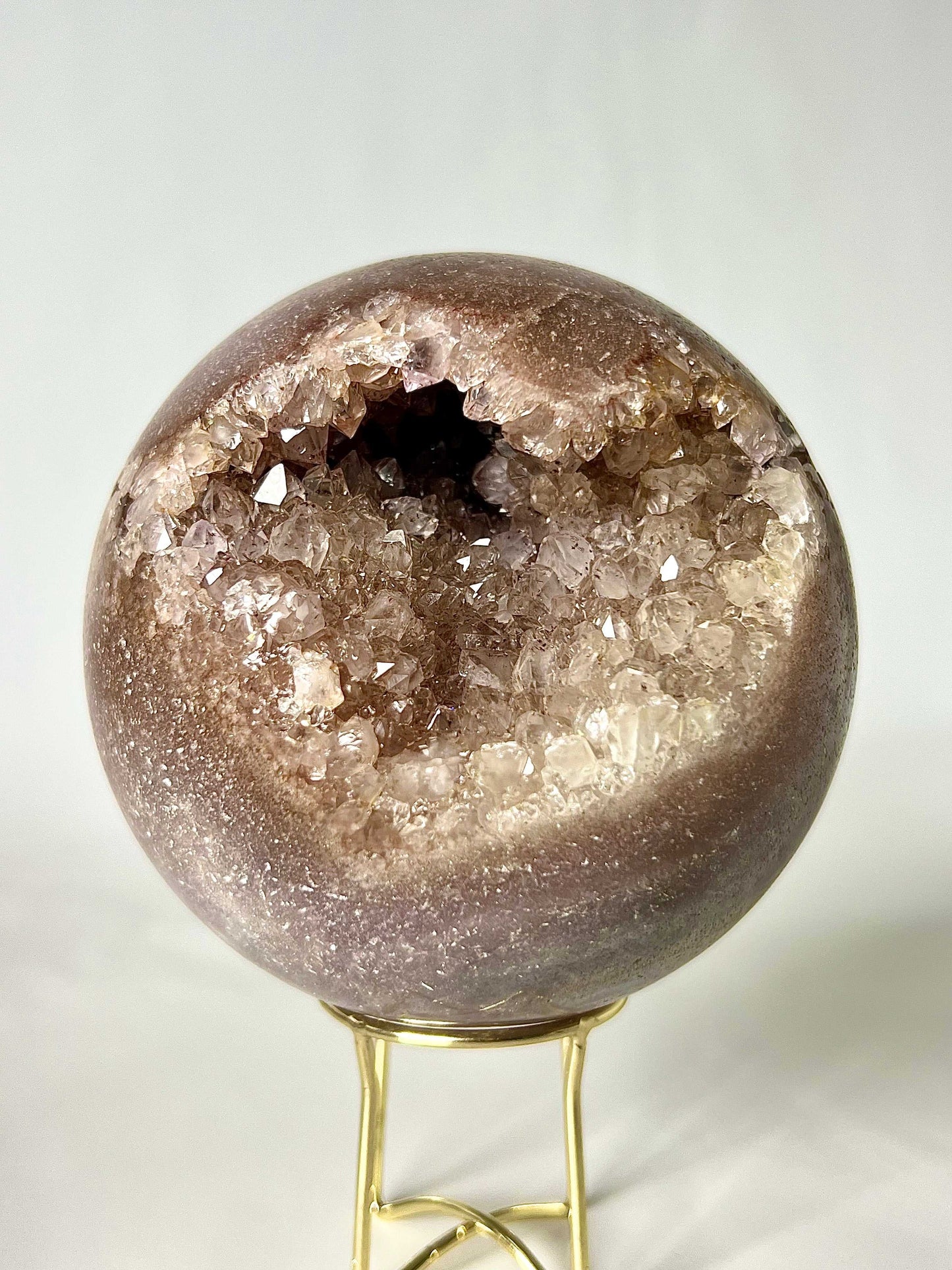 Pink Amethyst Sphere with druzy crystal cavity on gold stand, ideal for heart chakra healing and spiritual insight. Shop rare crystals NZ online.