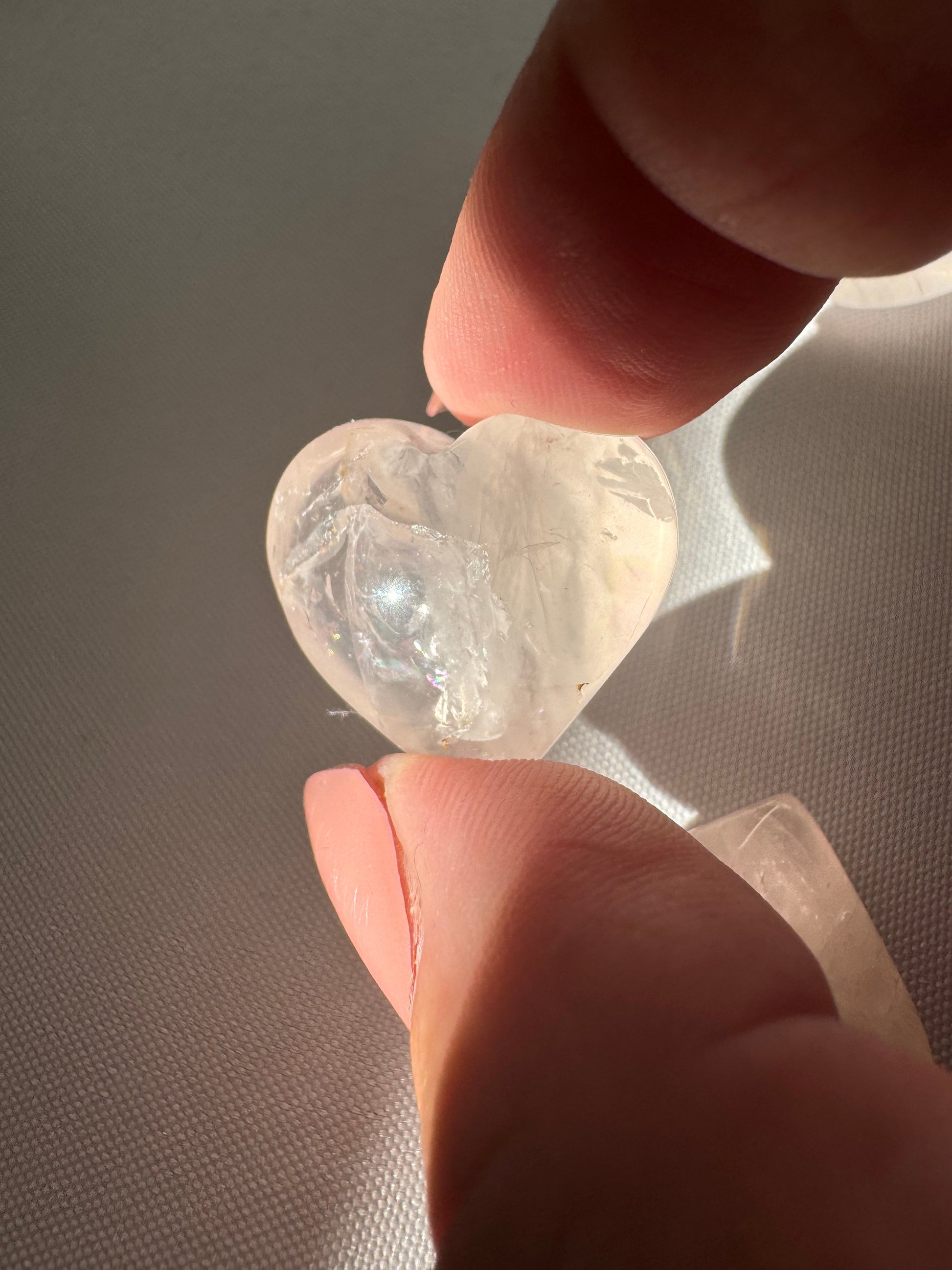 Close-up of a Mini Rose Quartz Crystal Heart | Bespoke Crystals held between fingers, highlighting its clarity and heart-shaped carving.