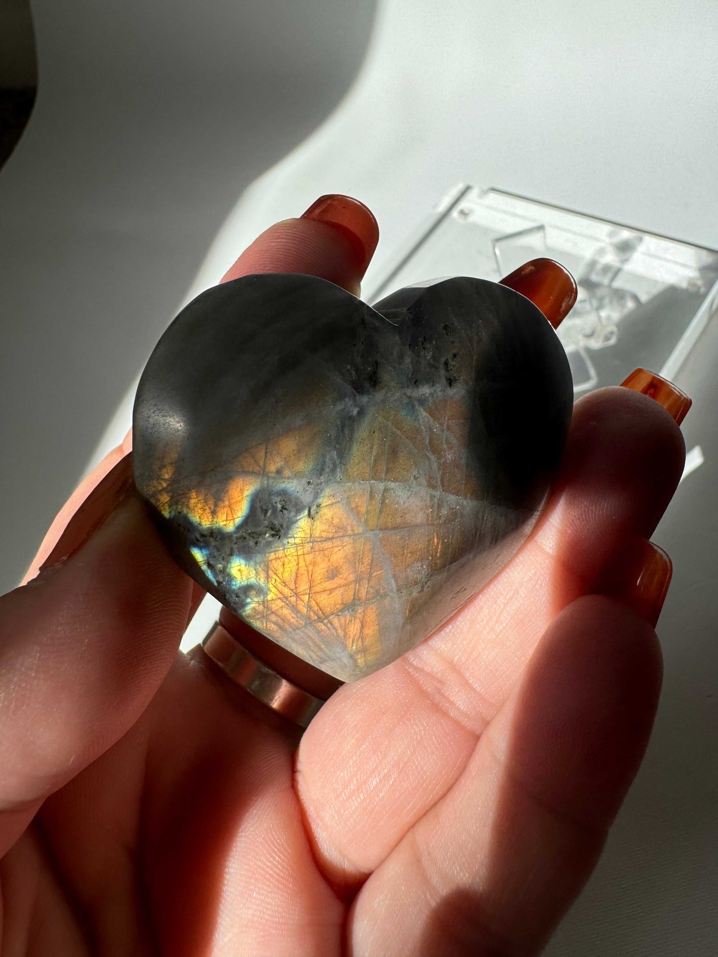 Hand holding Labradorite Puffy Heart #4 with vivid golden and blue flashes, highlighting the crystal's natural labradorescence and smooth finish.