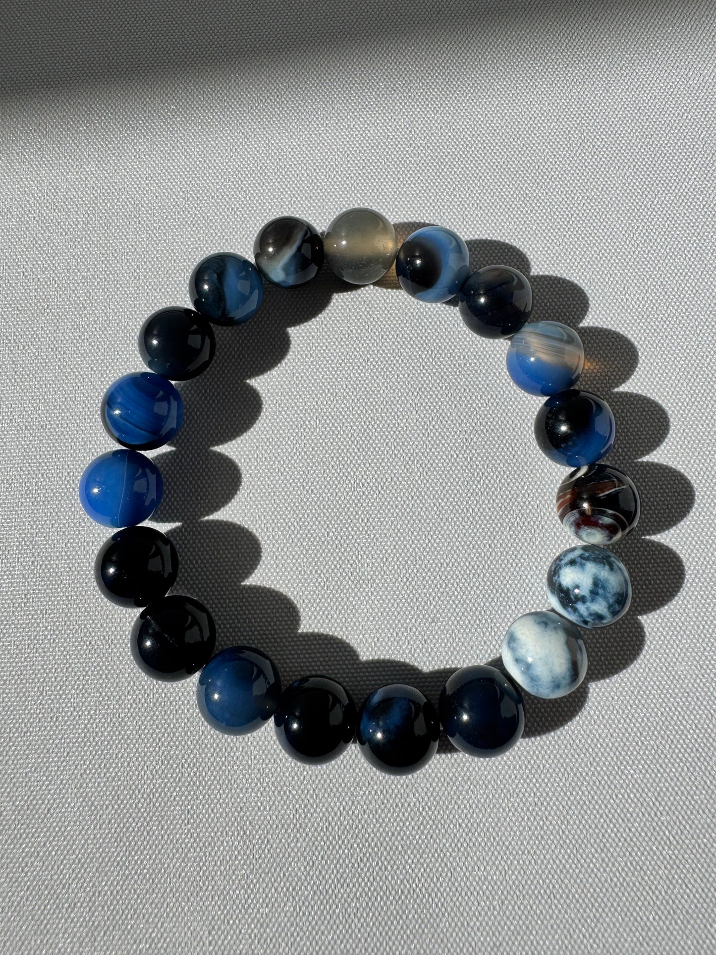 Elegant Blue Agate Crystal Bracelet 10mm with smooth, multishade blue stones, promoting peace and communication, available at Bespoke Crystals.