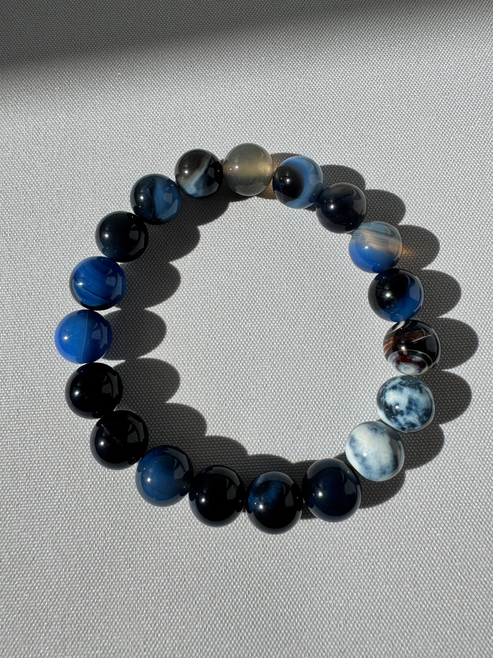 Elegant Blue Agate Crystal Bracelet 10mm with smooth, multishade blue stones, promoting peace and communication, available at Bespoke Crystals.