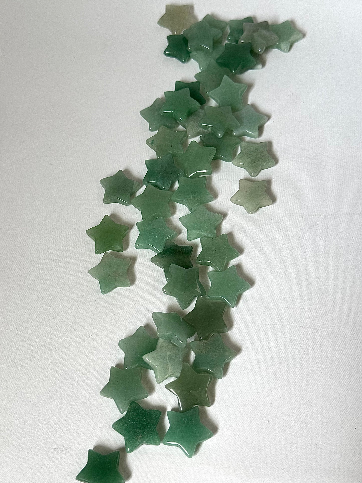 Loose Green Aventurine Crystal Stars arranged on white background, perfect for spiritual decor, or crystal healing practices.