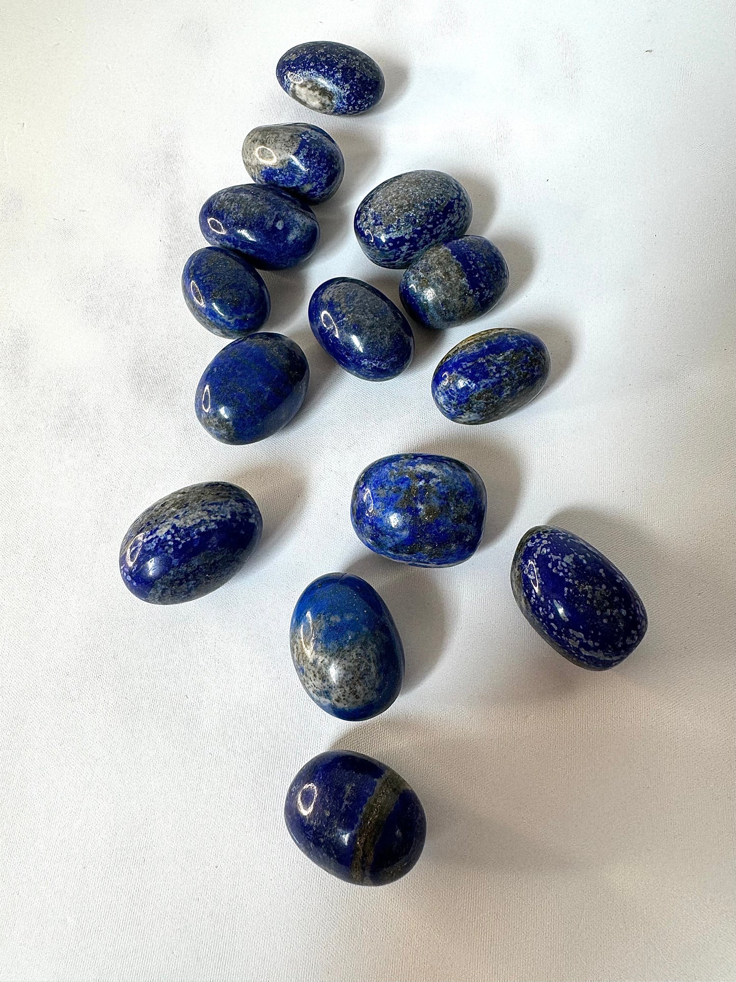 Top view of multiple Lapis Lazuli tumble stones with natural patterns, ideal for creative arts, crystal decor, or spiritual expression.