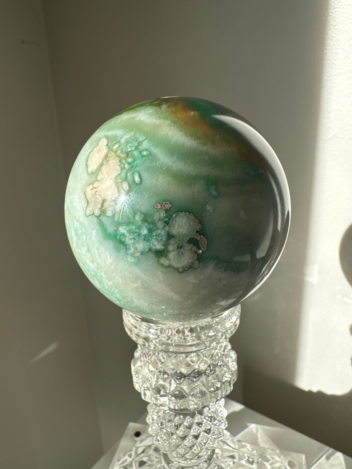 Green Flower Agate Sphere #3 showcasing pastel green swirls and white crystal blooms, a unique collectible for emotional healing and decor.