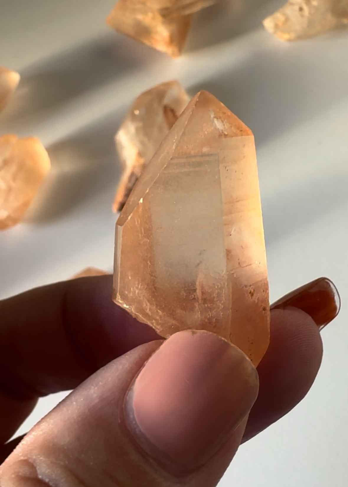 Hand holding a polished Lemurian Tangerine Crystal Quartz | Bespoke Crystals with rich orange tones, highlighting its unique growth patterns.