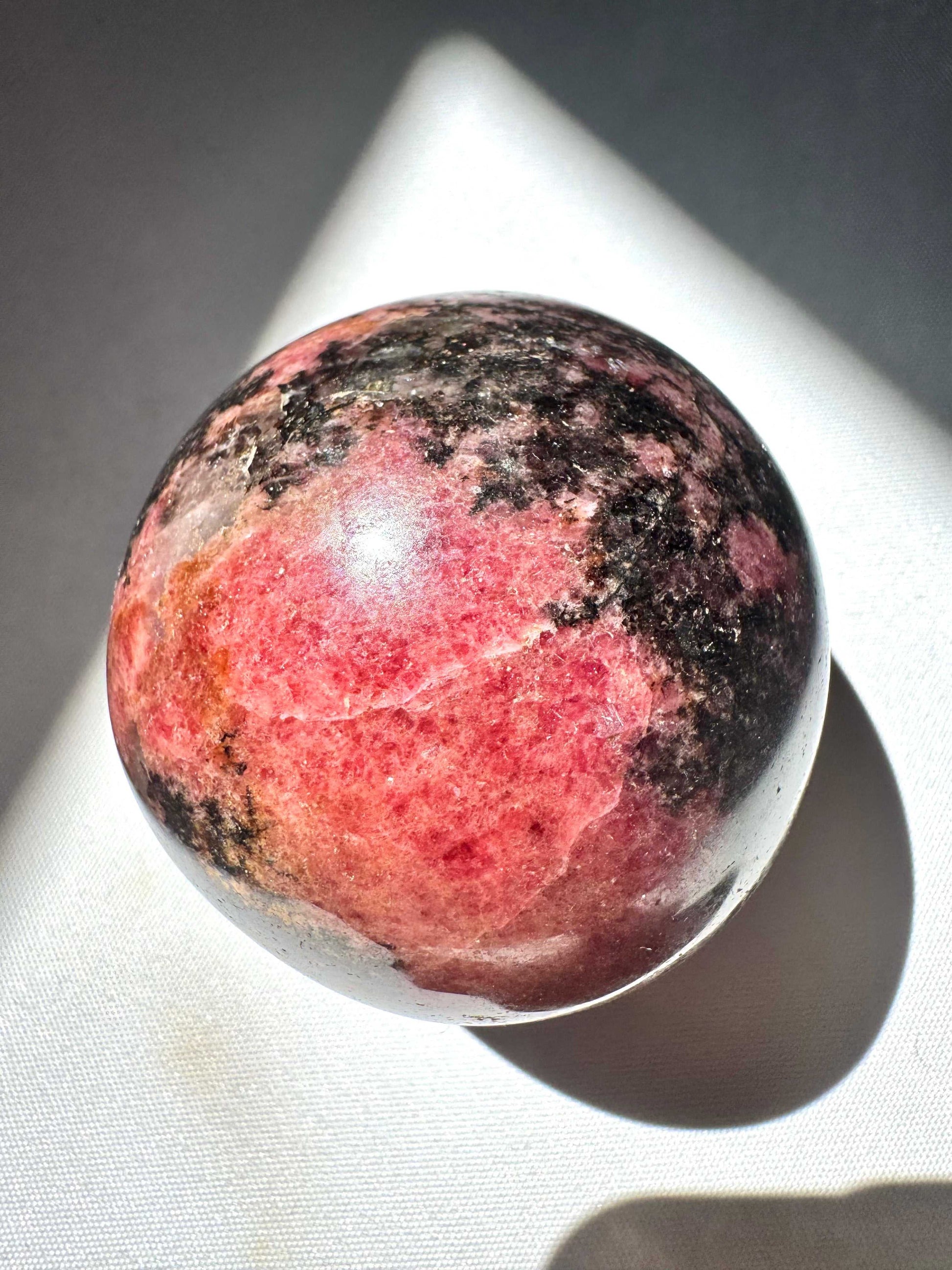 Rhodonite Sphere - Handcrafted Rhodonite crystal sphere featuring rich pink hues, perfect for love and positivity rituals.Buy Healing Crystals NZ |