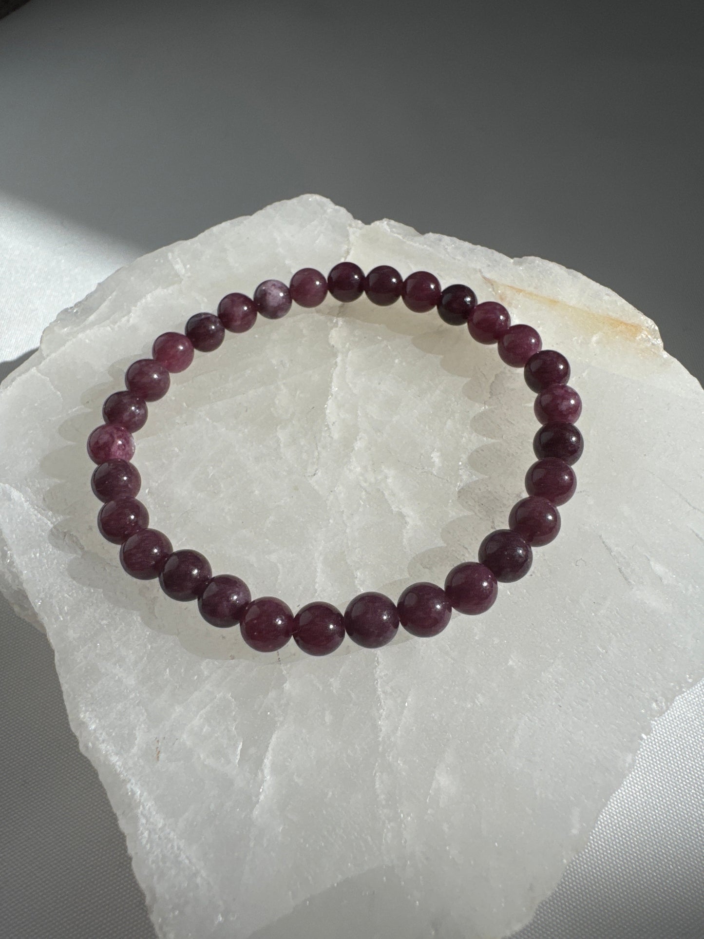 Garnet Crystal 6mm Bracelet | Bespoke Crystals with round garnet beads, shown on a translucent crystal slab for jewellery lovers in NZ.
