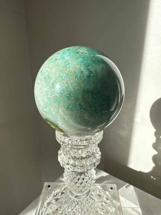 Green Flower Agate Sphere #3 with soft green hues and floral-like patterns, displayed on a crystal stand. Ideal for collectors and crystal healing.