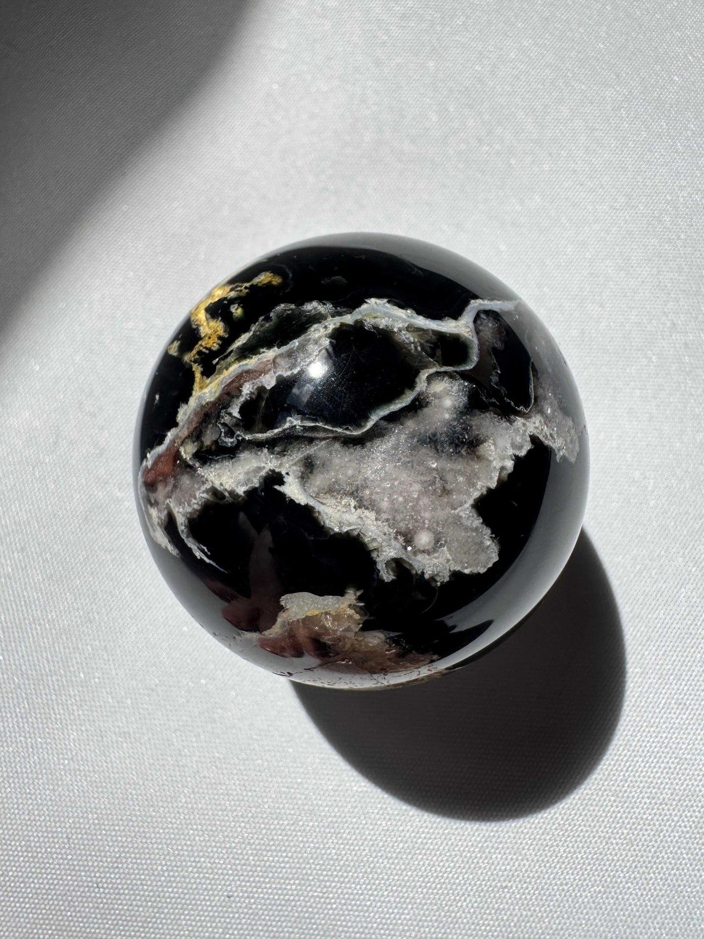 Polished Black Flower Agate Sphere featuring delicate pink and yellow flower-like patterns, perfect for spiritual growth and decor | Healing Crystals NZ