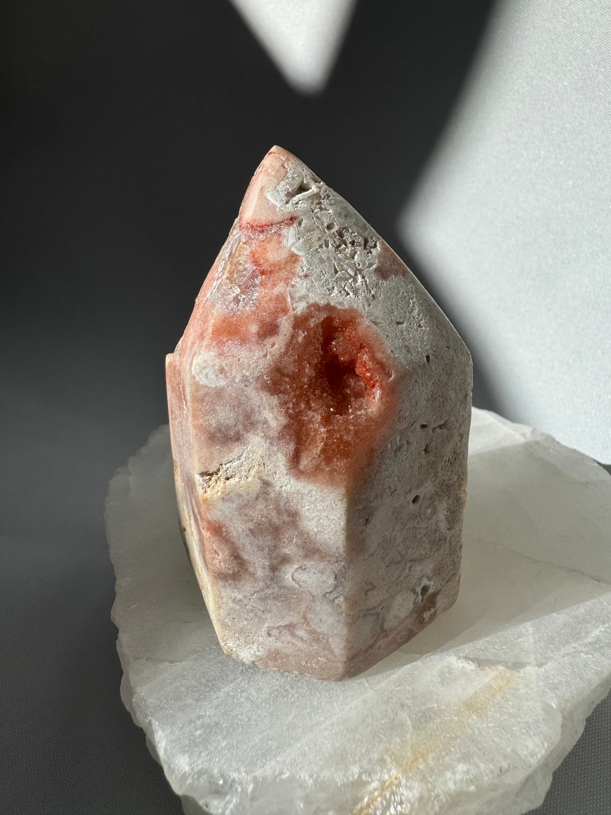 Side view of Pink Amethyst Crystal Tower featuring natural red and white mineral patterns with a small geode opening. A unique collectible crystal piece.