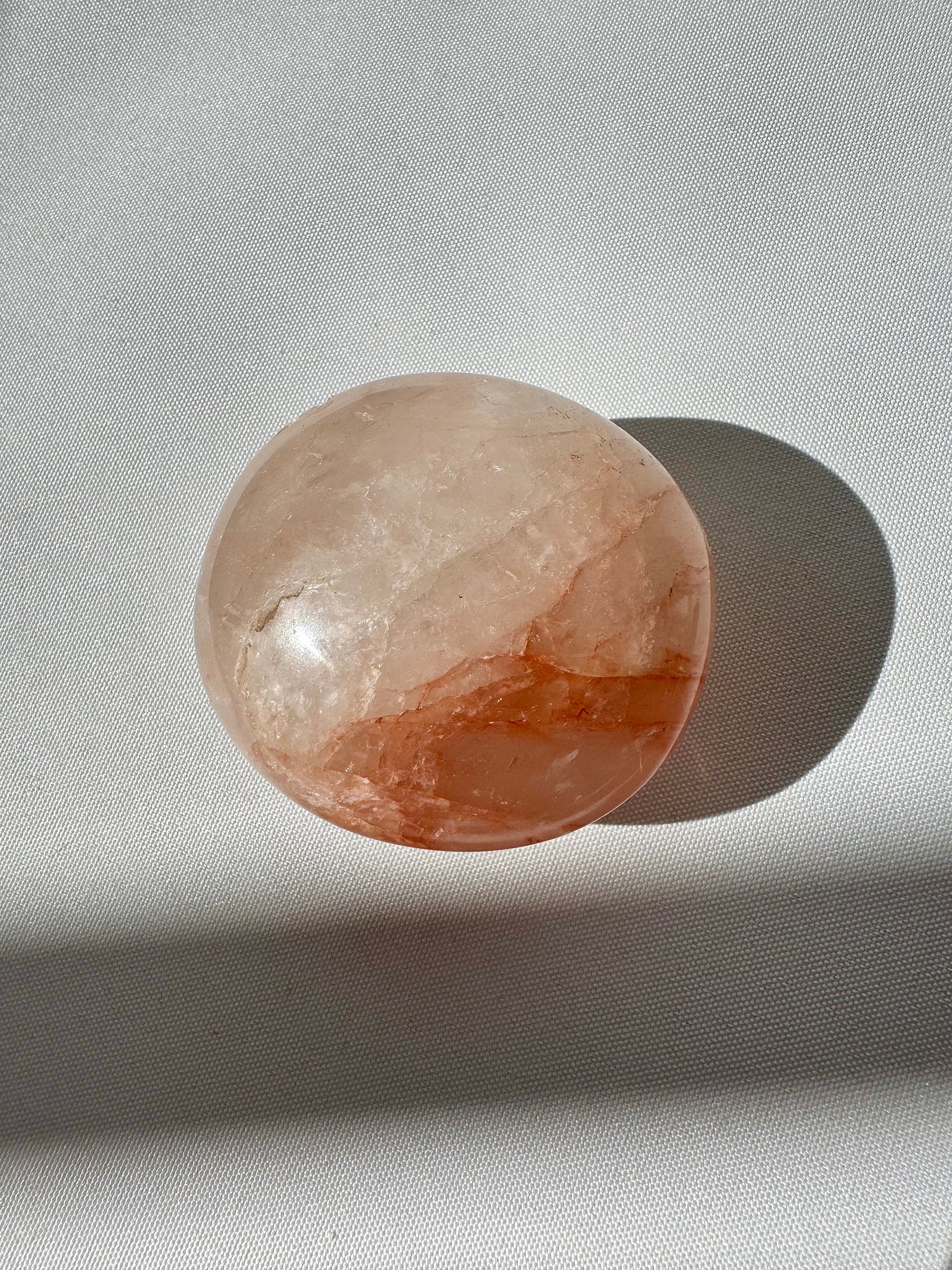 Light-toned Fire Quartz Palm Stone with soft orange inclusions, polished for use in meditation, grounding, and bespoke crystal collections.