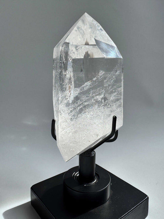 Polished Lemurian Quartz Crystal on rotating black stand with radiant clarity, ideal for meditation and display. Featured in Crystals NZ collection.