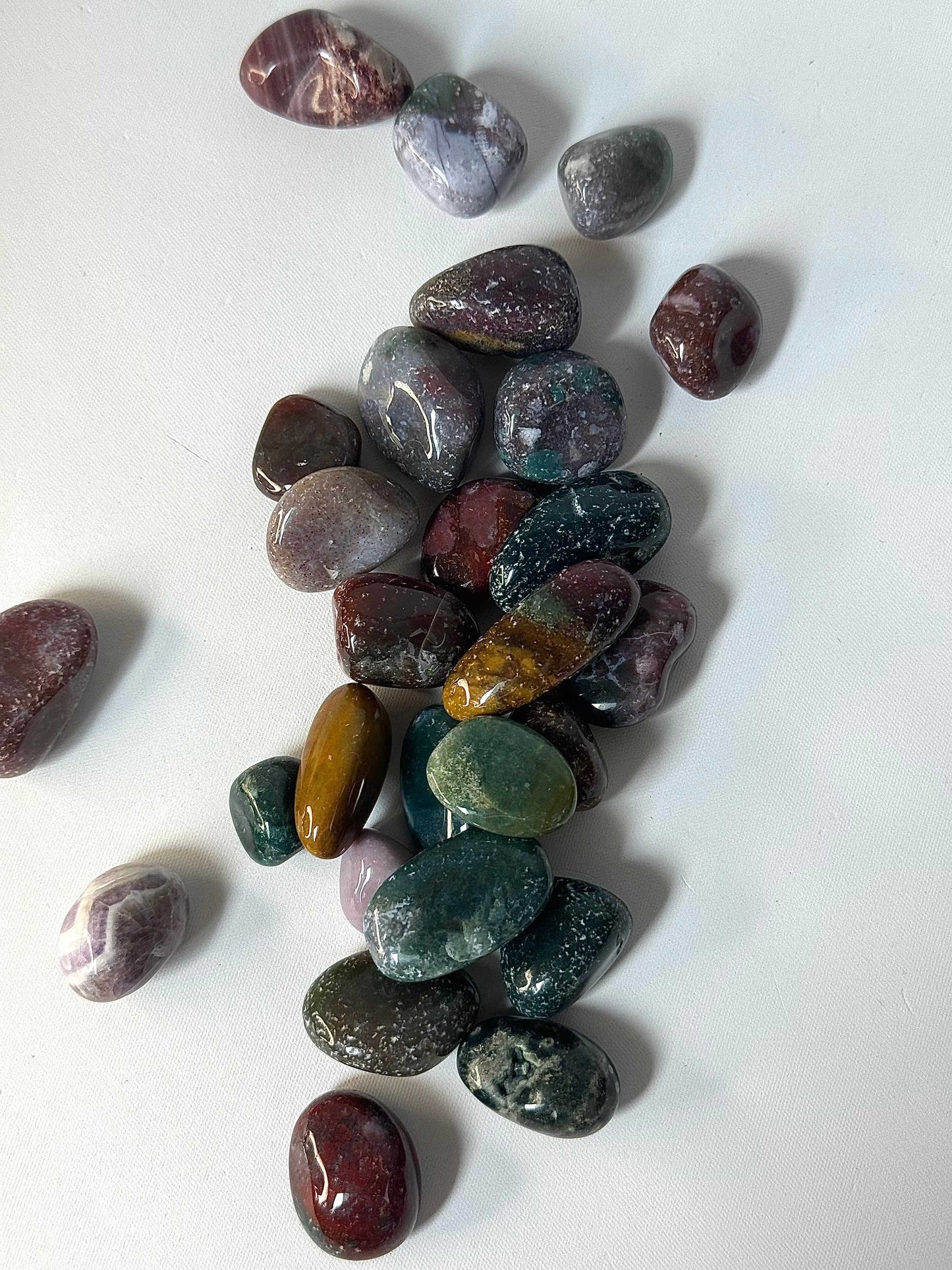 Ocean Jasper Crystal Tumble Stones - Healing Benefits | Self Love. Assorted Ocean Jasper stones in green, purple, and gold hues for crystal collectors.