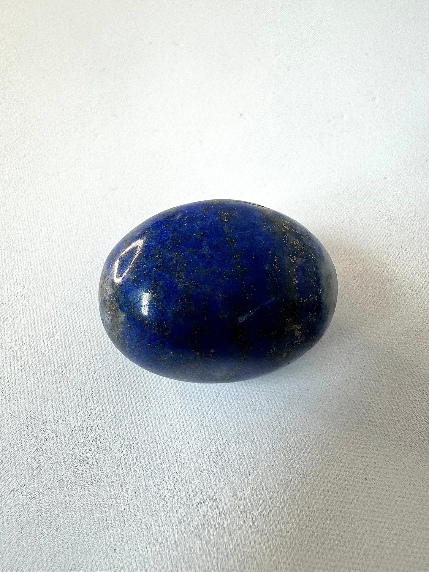 Single Lapis Lazuli tumble stone showcasing rich blue hues with subtle pyrite flecks, perfect for crystal healing or artistic embellishment.
