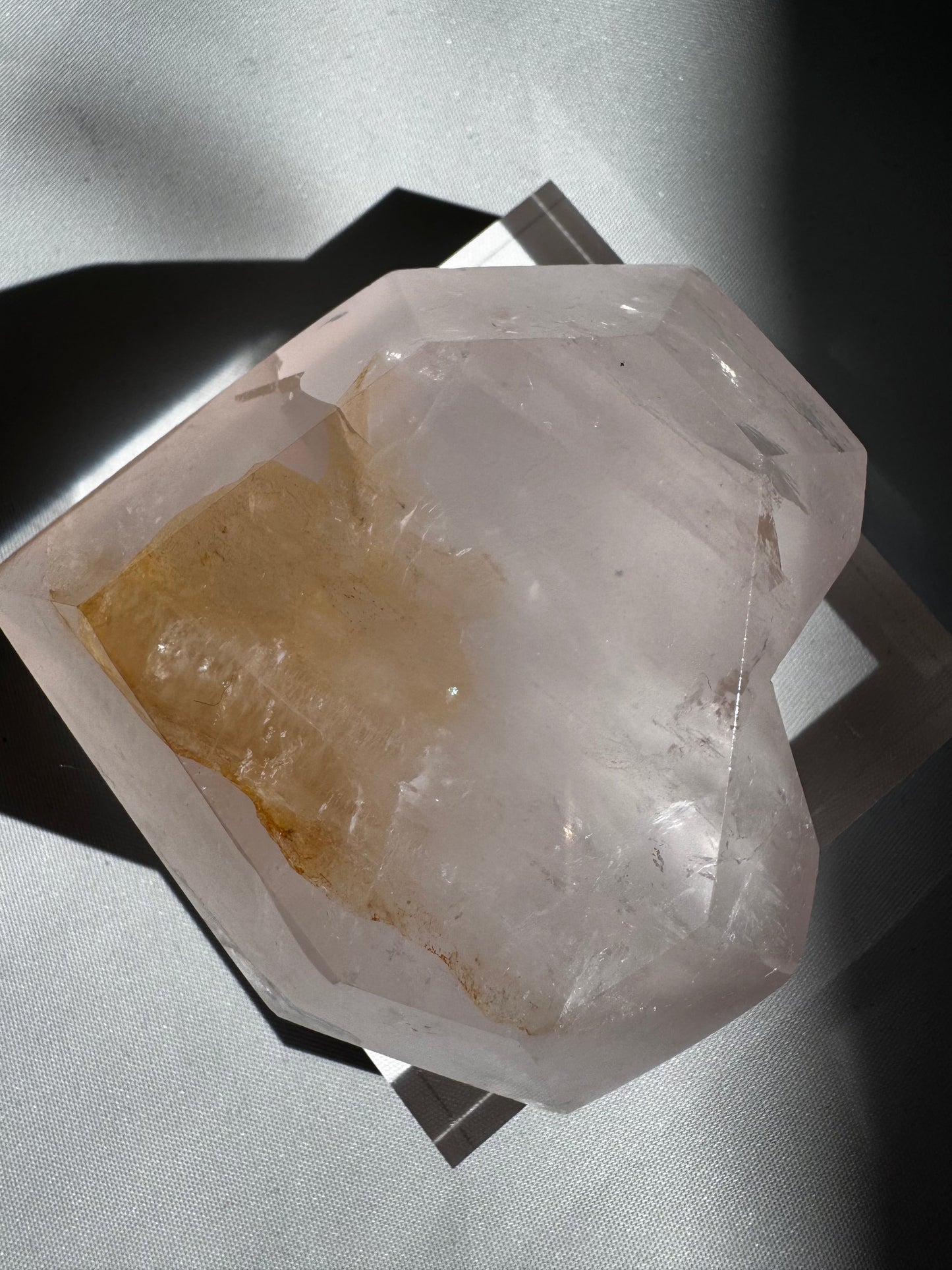 Unique Faceted Rose Quartz Heart with golden mineral inclusions and natural rainbows, showcased in angled lighting.