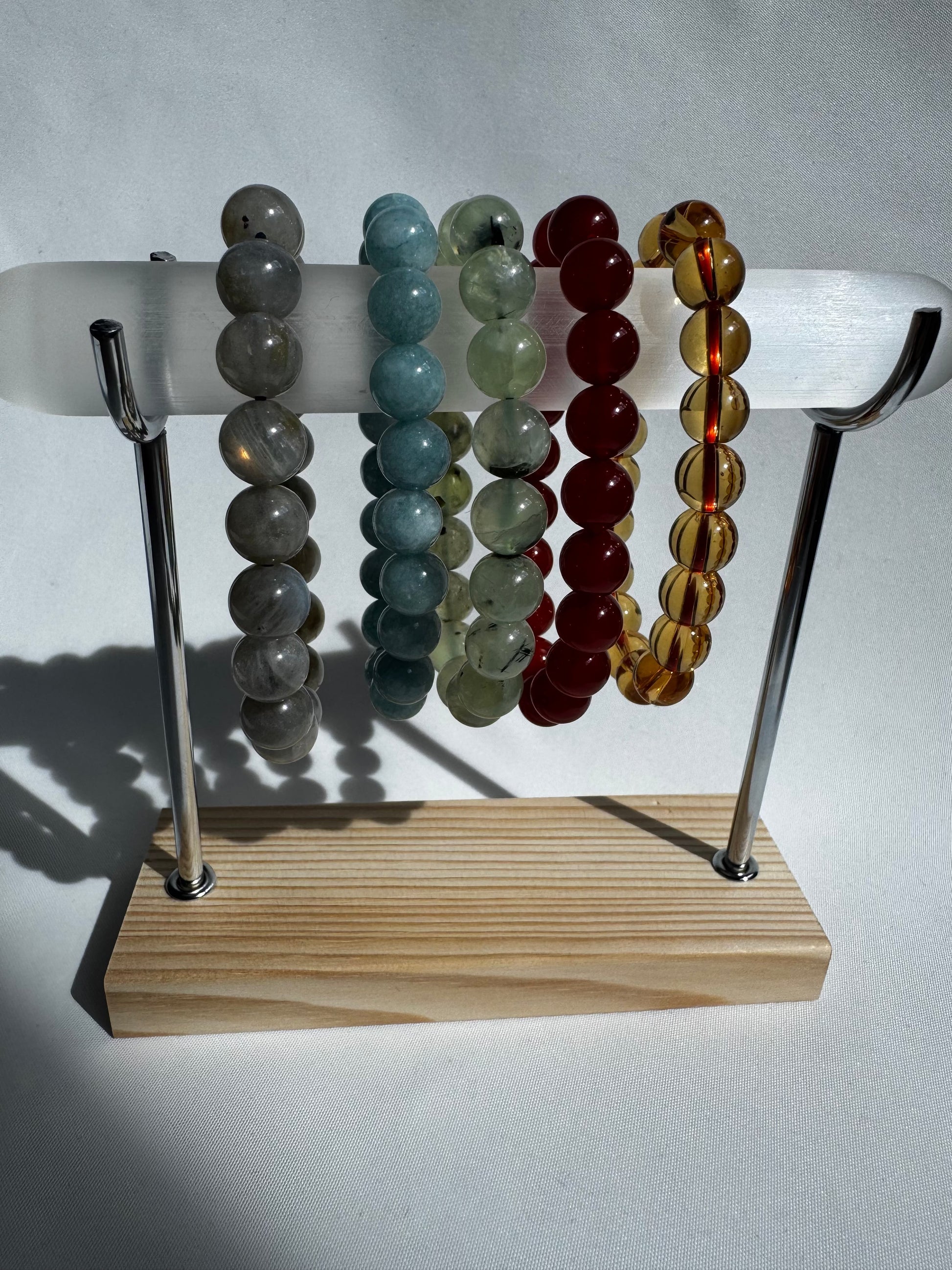 Selenite Bracelet Holder - Display Stand showcasing gemstone bracelets in natural light. Stylish jewellery organizer with a sleek wood and metal design.