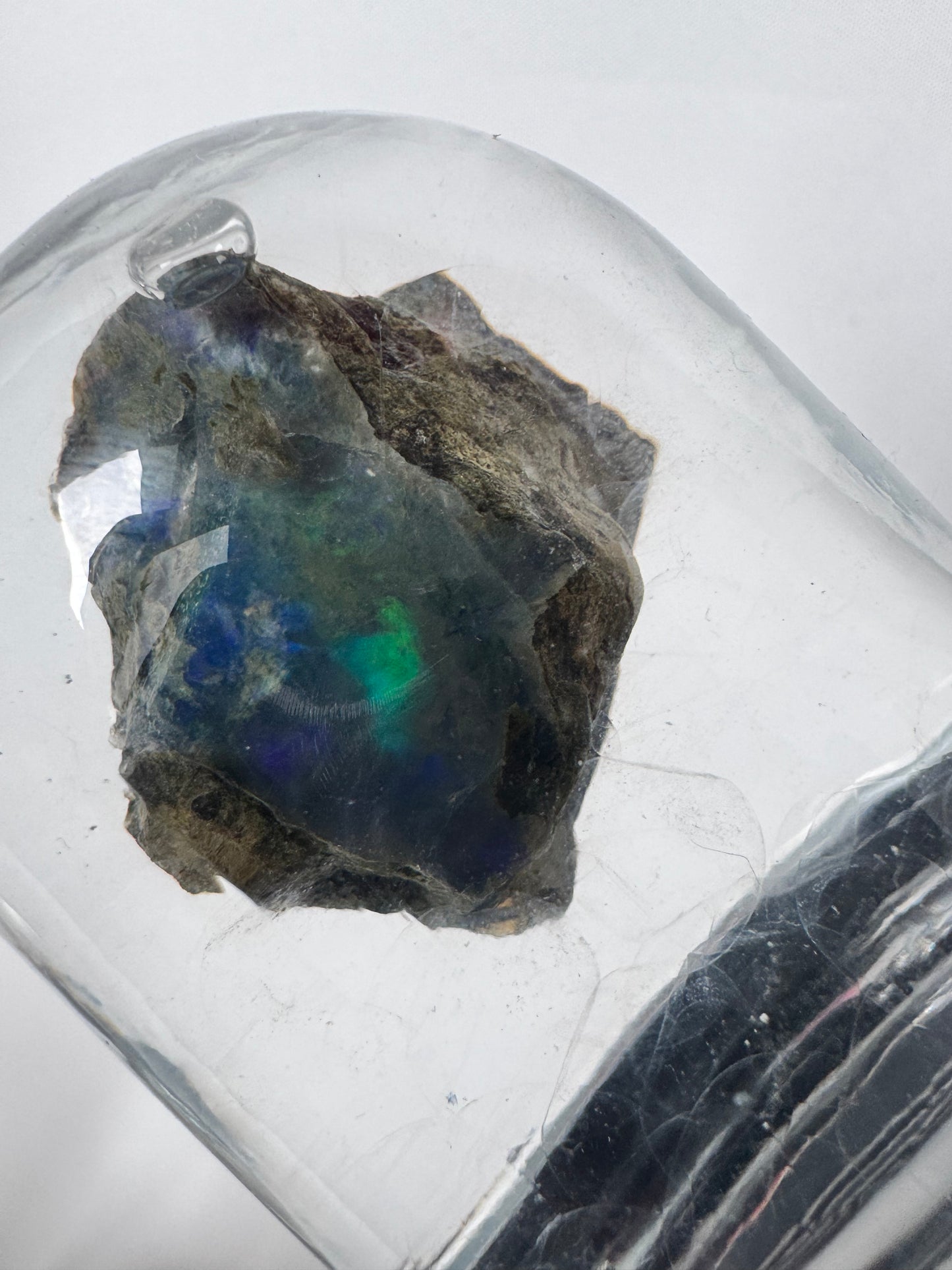 Close-up of Welo Ethiopian Water Opal under glass dome, highlighting its unique iridescent hues ideal for spiritual insight and transformation.