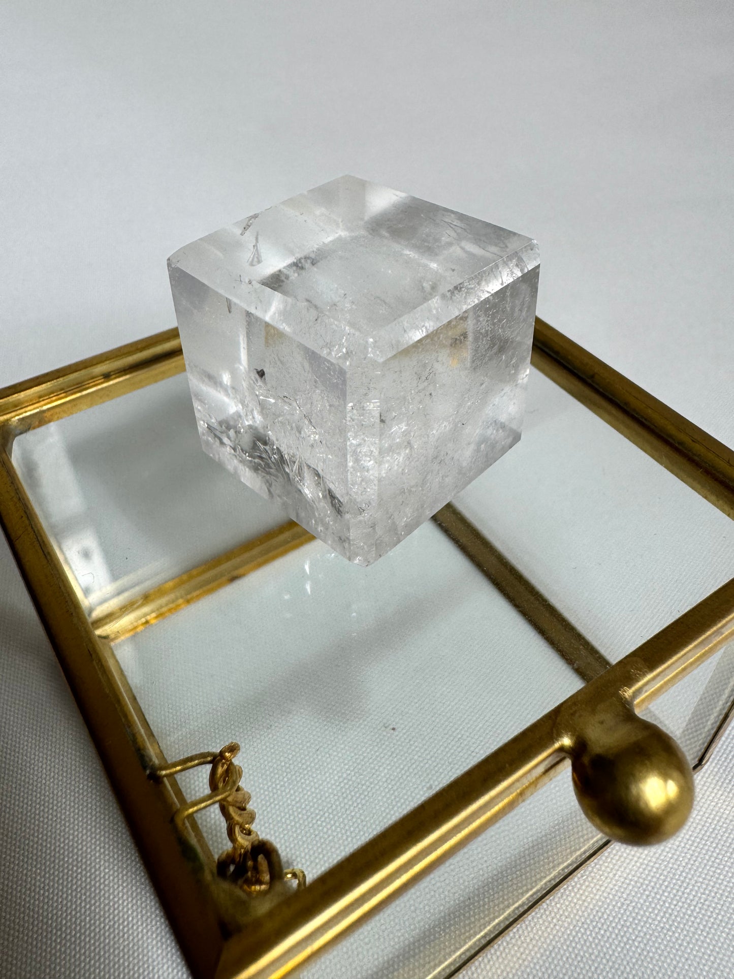Lemurian Hexahedron Cube featured on a brass-trimmed glass box, showcasing its clarity and sacred geometry for spiritual use.