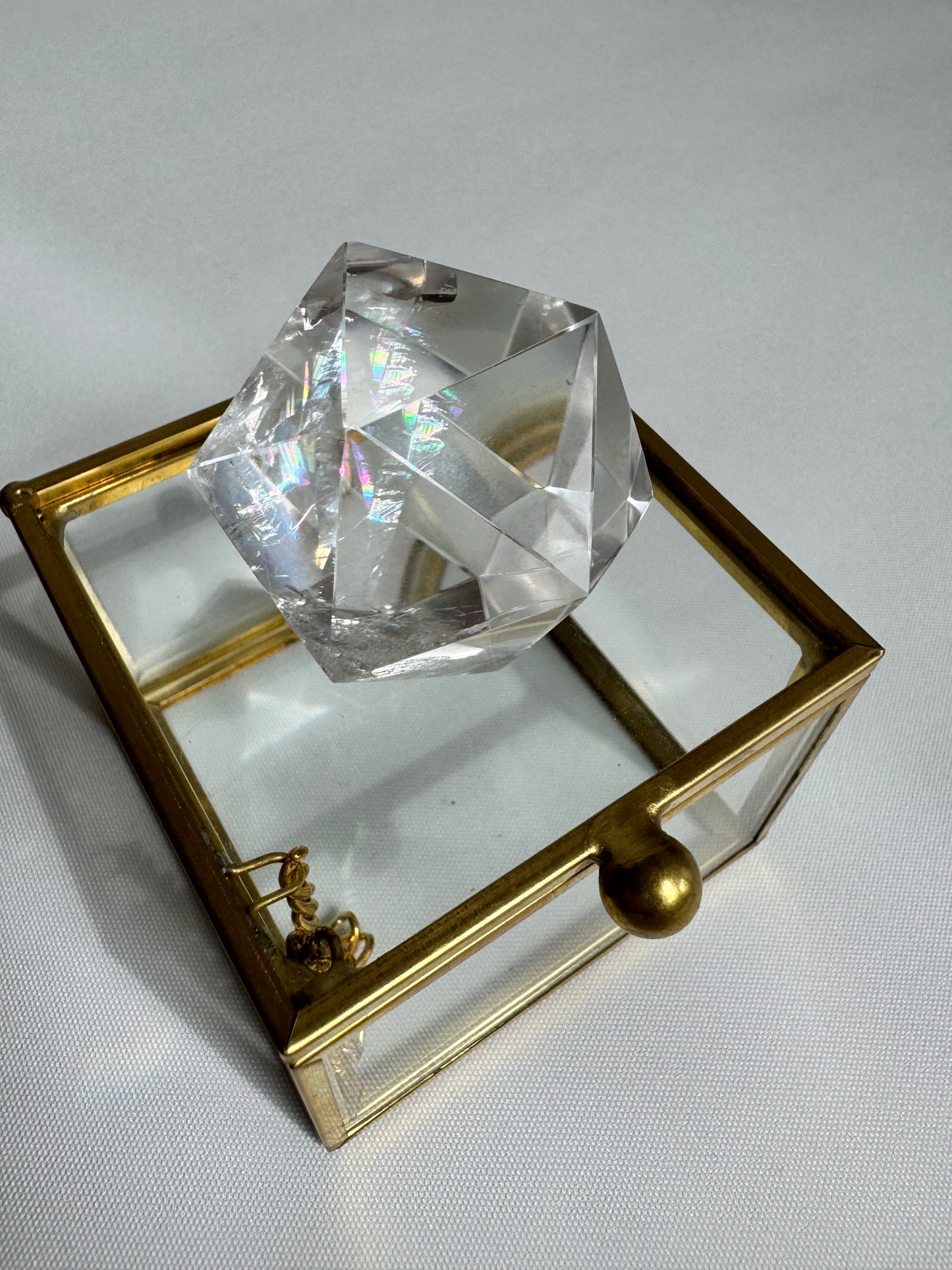 Lemurian Crystal Dodecahedron displayed on a decorative glass box, emphasizing its sacred geometry and use in energy toolkits.