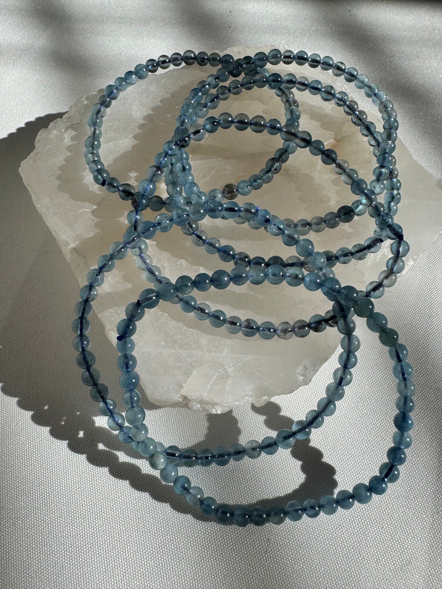 Multiple aquamarine beaded bracelets on white stone | Best crystal bracelets Nz