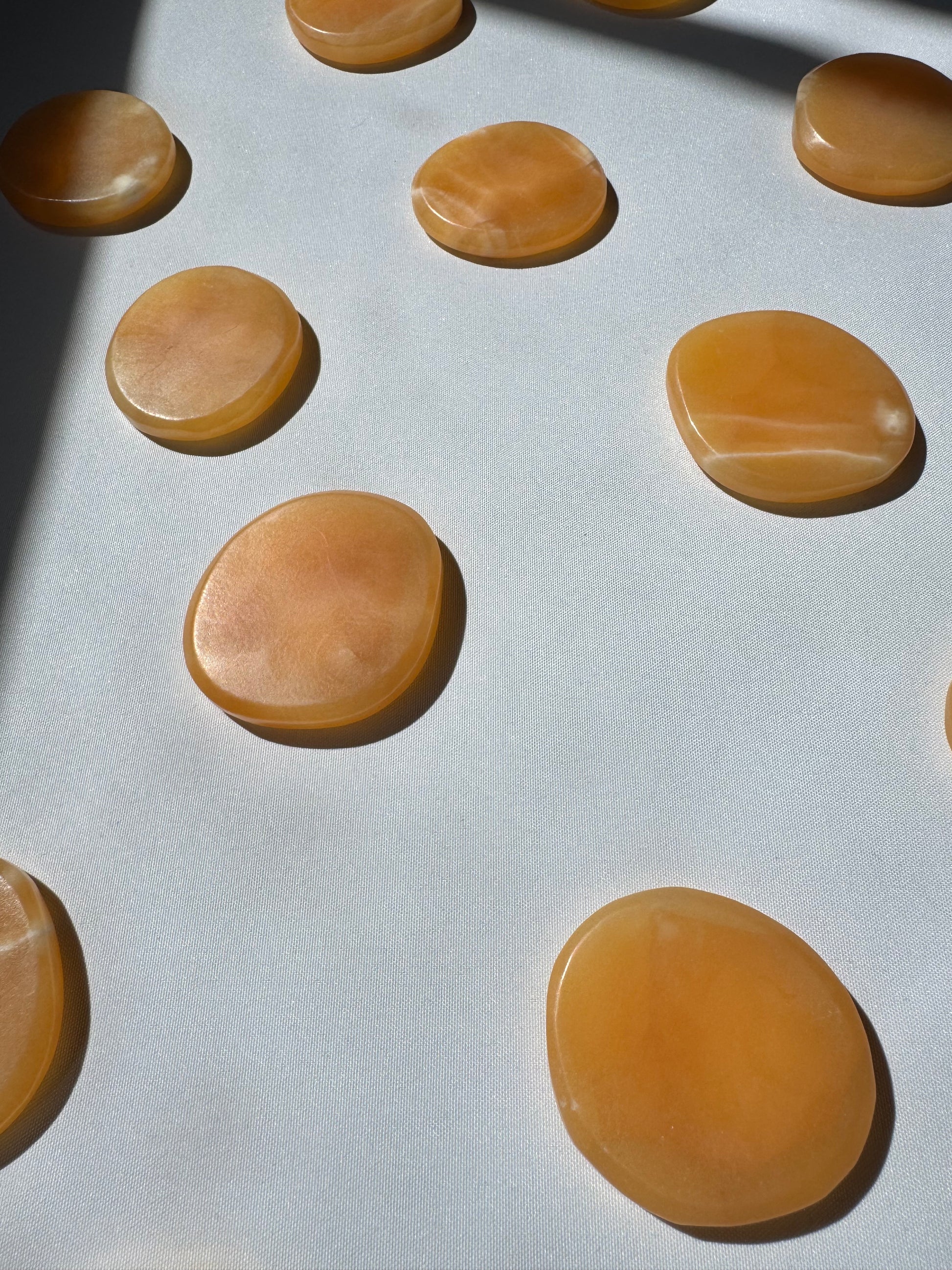 Multiple Orange Calcite Crystal Sun Discs | Bespoke Crystals arranged in sunlight, highlighting their radiant glow and collectible quality.