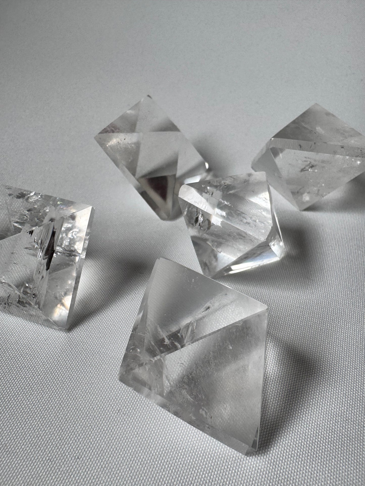 Lemurian Quartz Octahedrons arranged on textured surface, showcasing clarity and geometric precision for meditation use.
