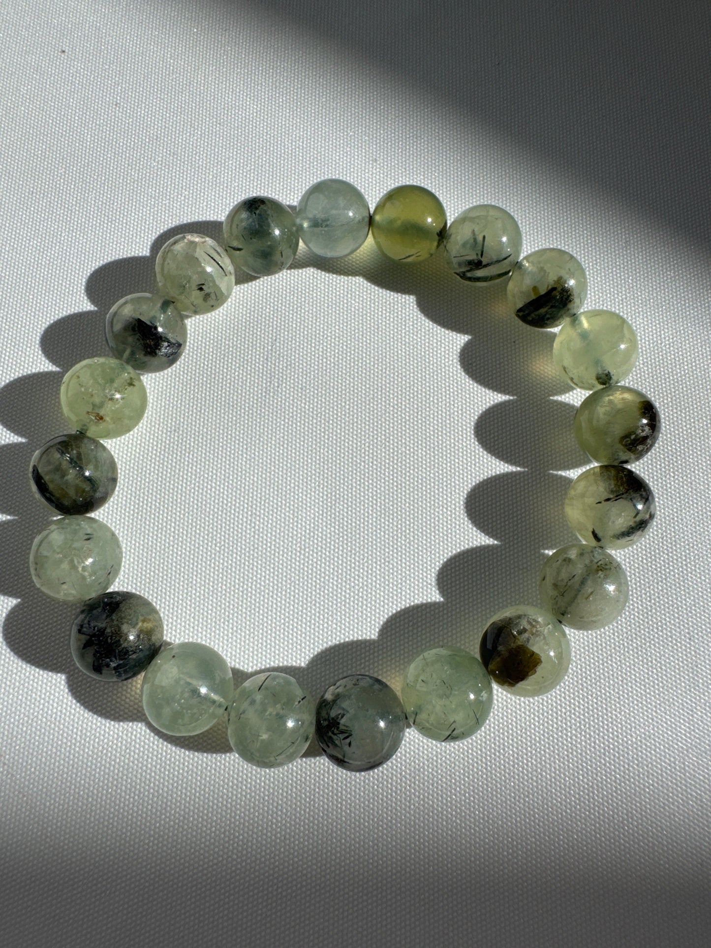 Prehnite Crystal Bracelets 10mm with natural green gemstone beads, shown under sunlight to highlight clarity and unique inclusions.