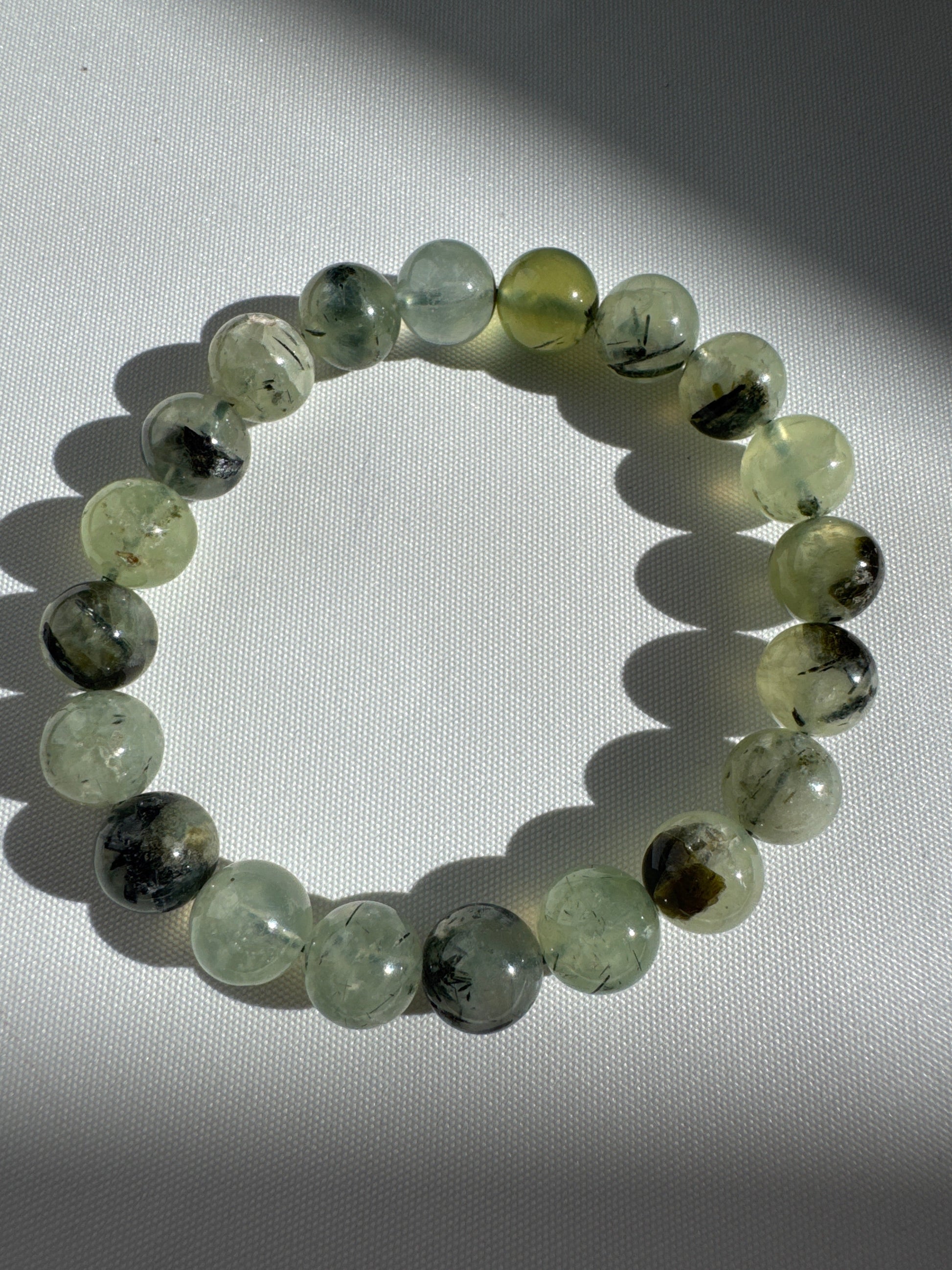 Prehnite Crystal Bracelets 10mm with natural green gemstone beads, shown under sunlight to highlight clarity and unique inclusions.
