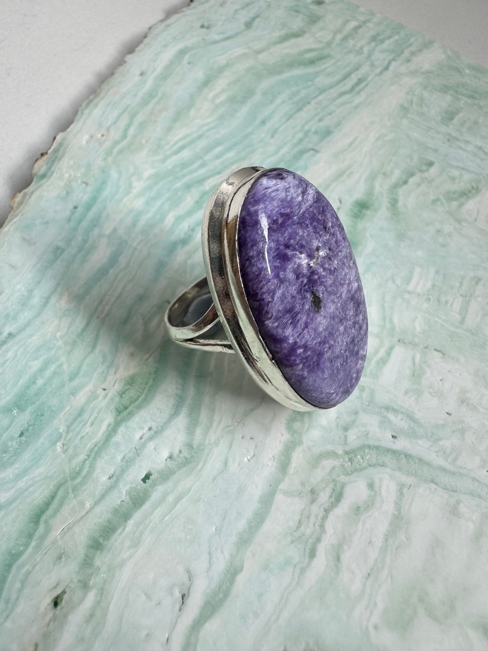 Angled view of Large Charoite Crystal Ring highlighting the textured purple gemstone and sterling silver band, a bold accessory in gemstone rings.