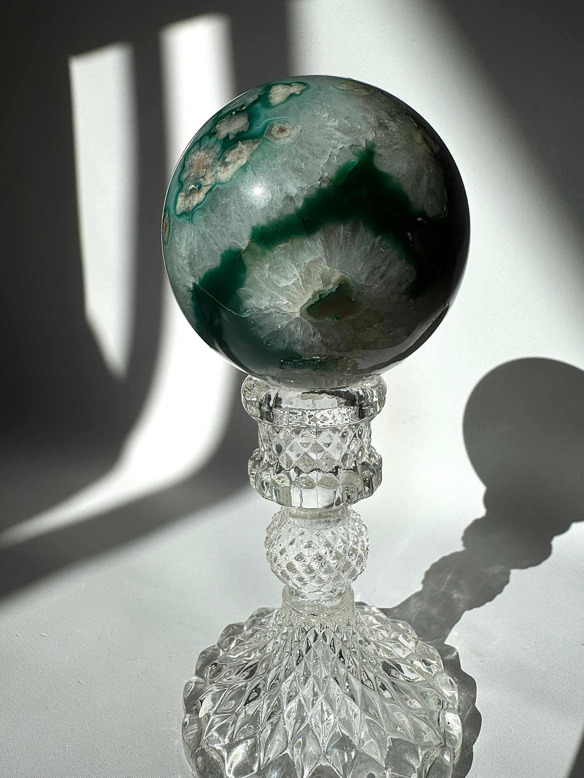 Green Flower Agate Crystal Sphere #1 featuring a deep green band and floral formations, elegantly set on a cut-glass stand for collectors.