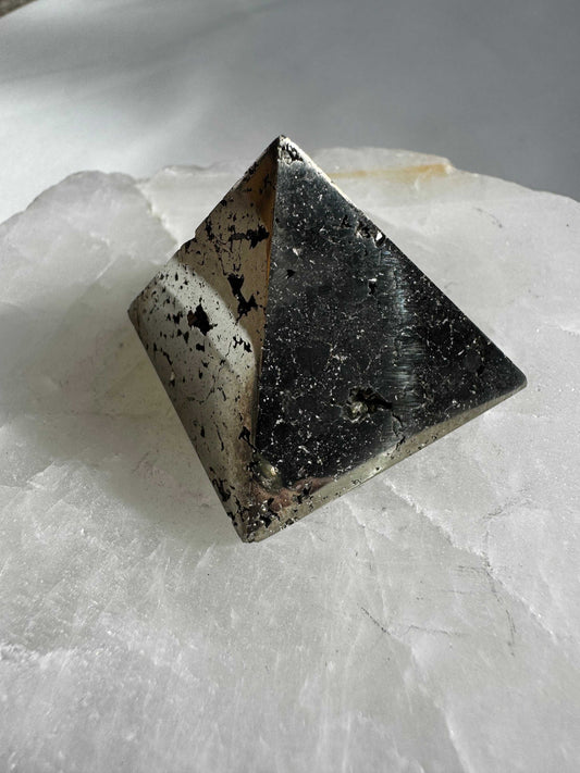 Pyrite Pyramid #3 with metallic luster and natural texture, displayed on a white crystal slab for wellness and abundance decor.