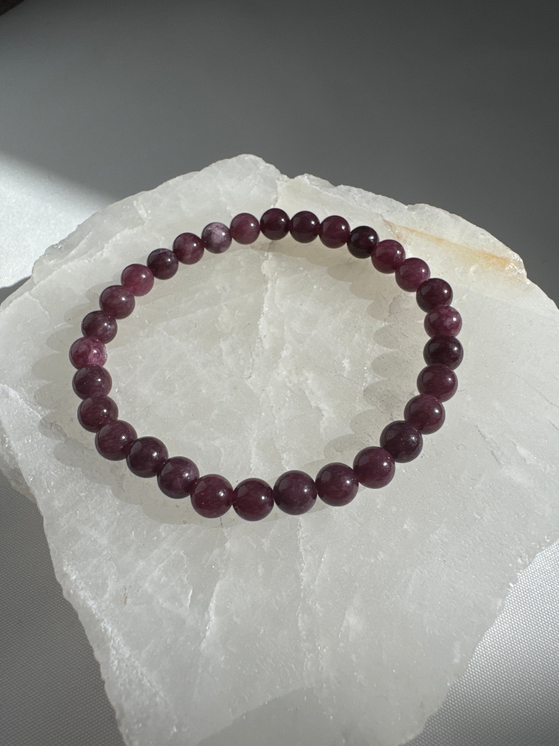 Garnet Crystal 6mm Bracelet | Bespoke Crystals with round garnet beads, shown on a translucent crystal slab for jewellery lovers in NZ.