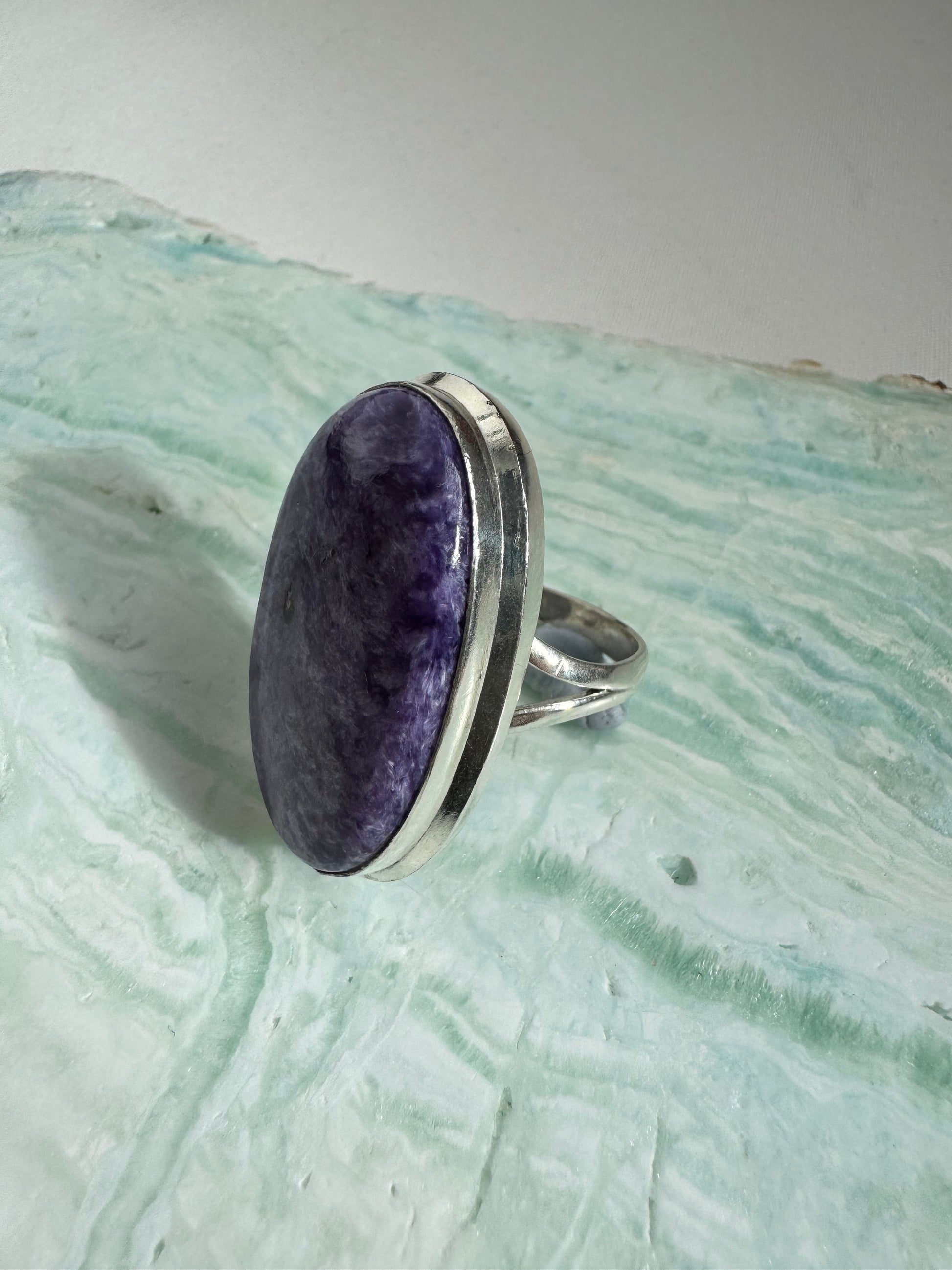 Side view of Large Charoite Crystal Ring featuring a polished purple stone with natural patterns in a silver bezel setting, perfect for statement jewelry.