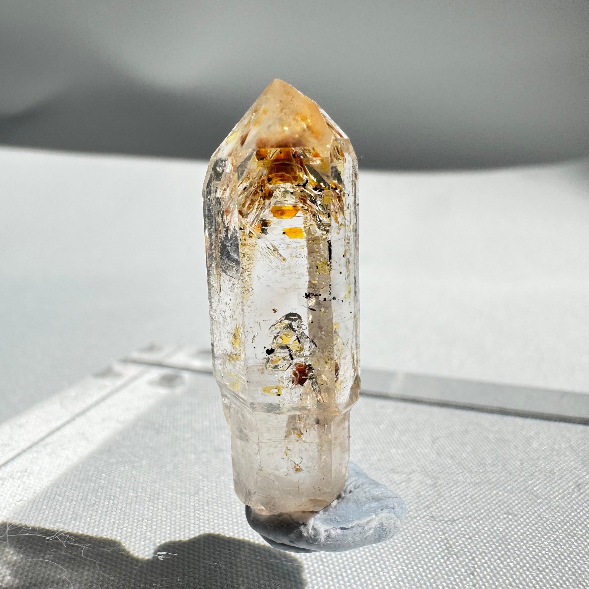 Polished UV Reactive Firefly Enhydro Quartz crystal showcasing golden petroleum inclusions, ideal for gemstone collectors.