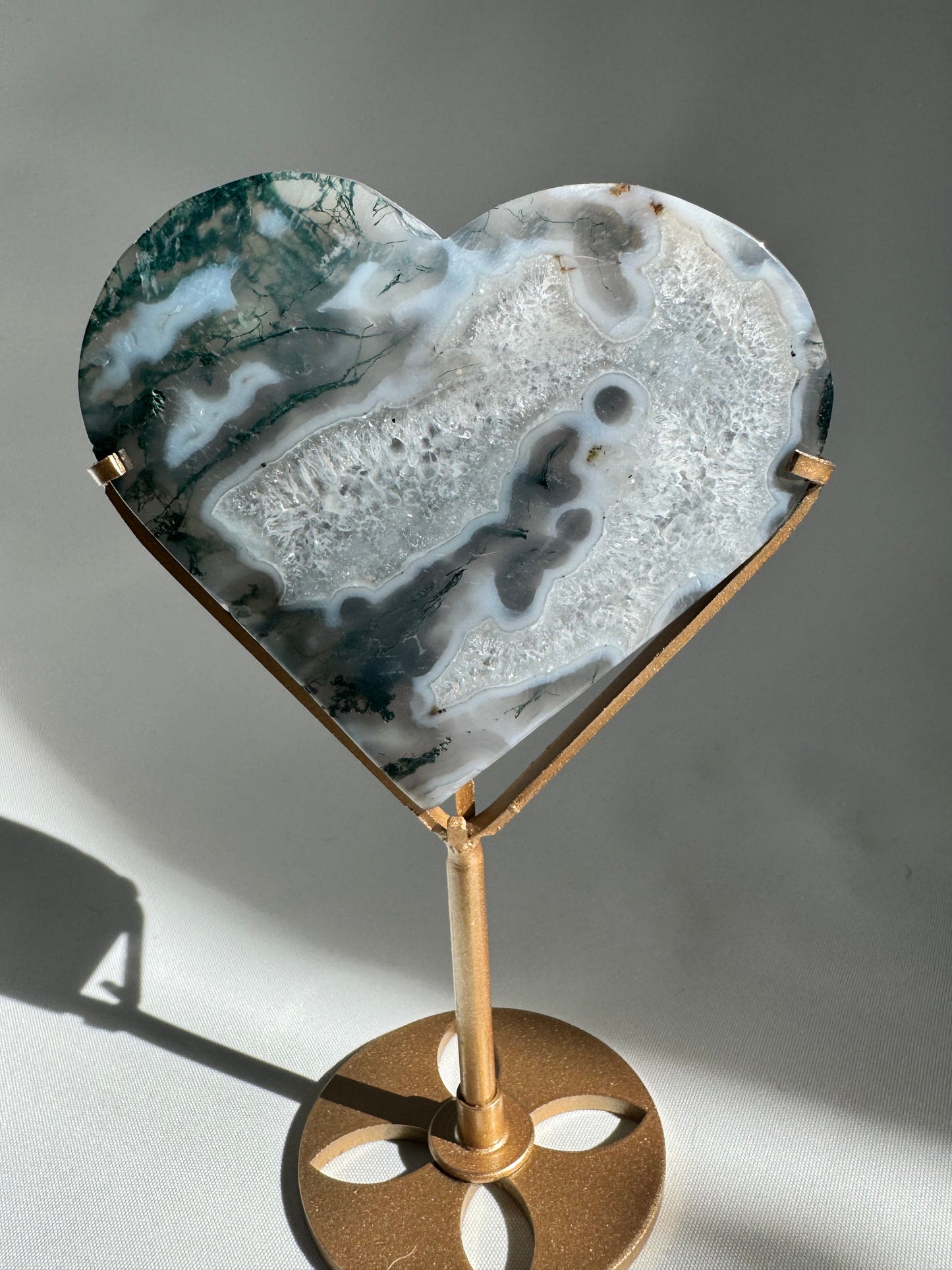 Decorative Moss Agate Heart crystal on gold stand, showcasing natural stone patterns