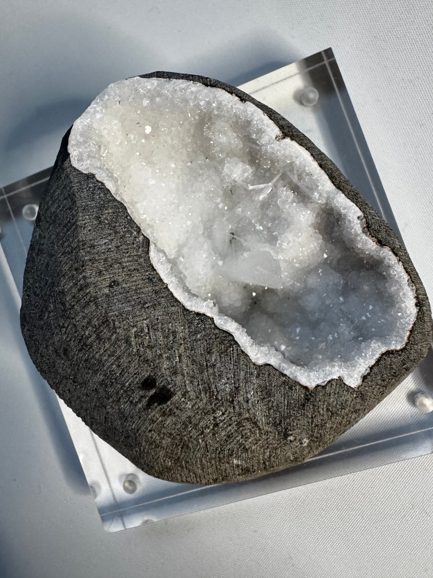Scolecite & Quartz Crystal Geode with radiant white needle-like crystals inside a dark gray stone shell, ideal for mineral collectors and crystal healing.